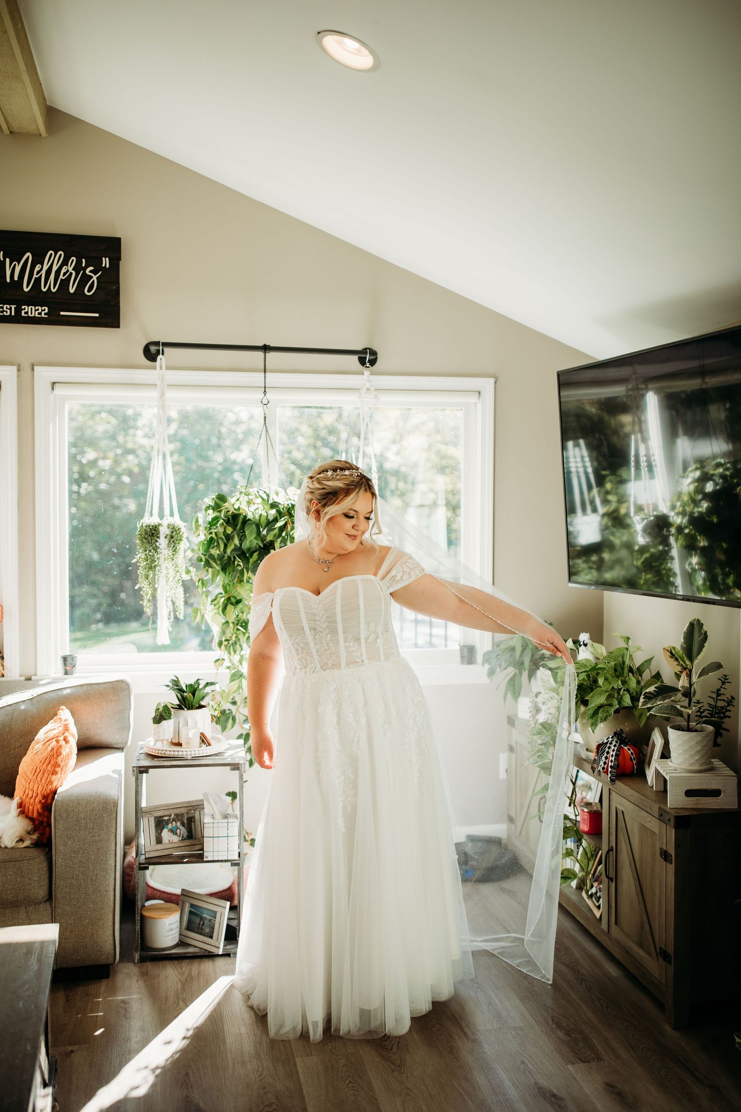 Cindy, the bride, holds her veil to the side like a cape, catching the light.