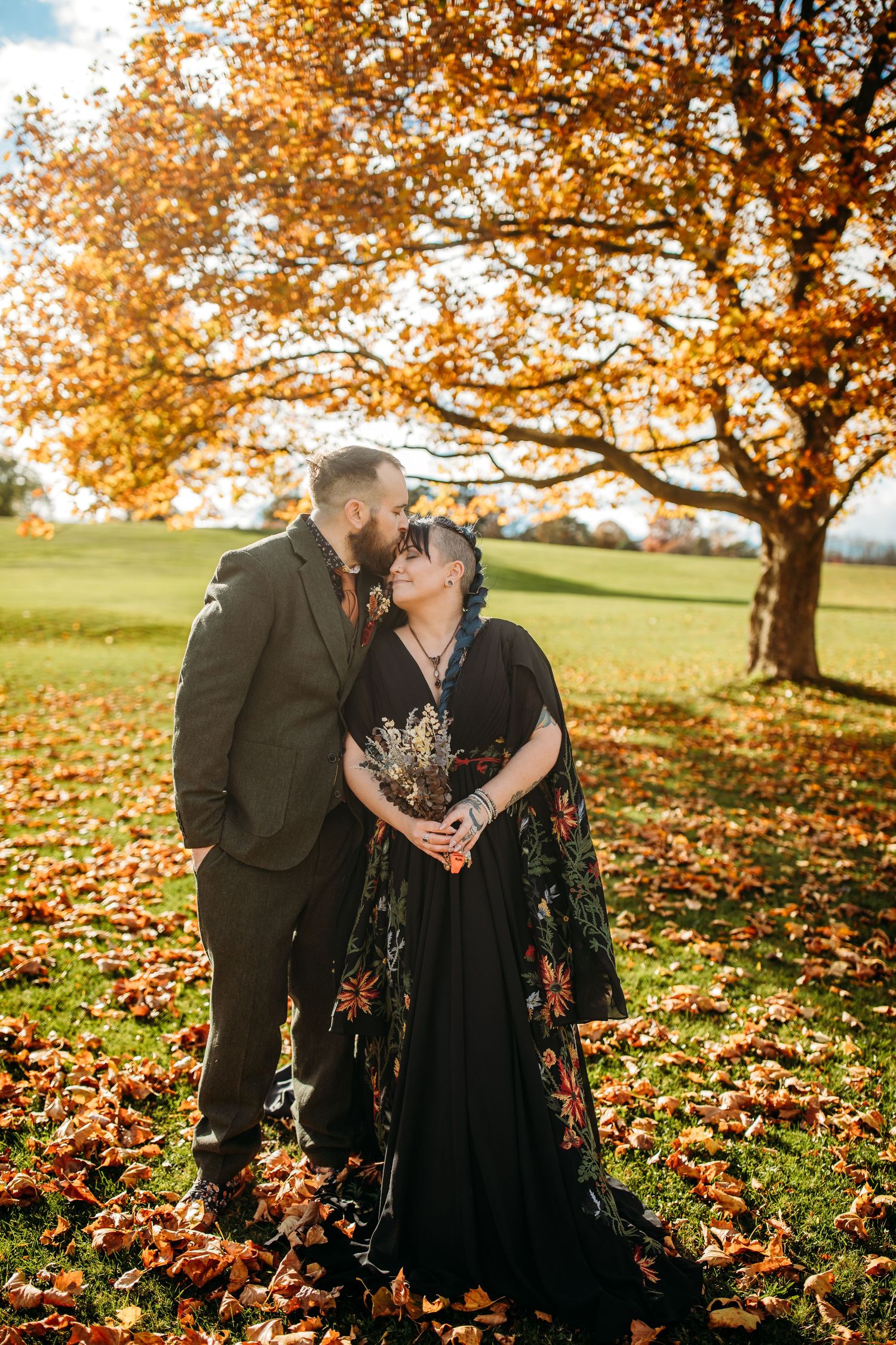 The bride is wearing a black floral dress, and the groom has a brown suit on.