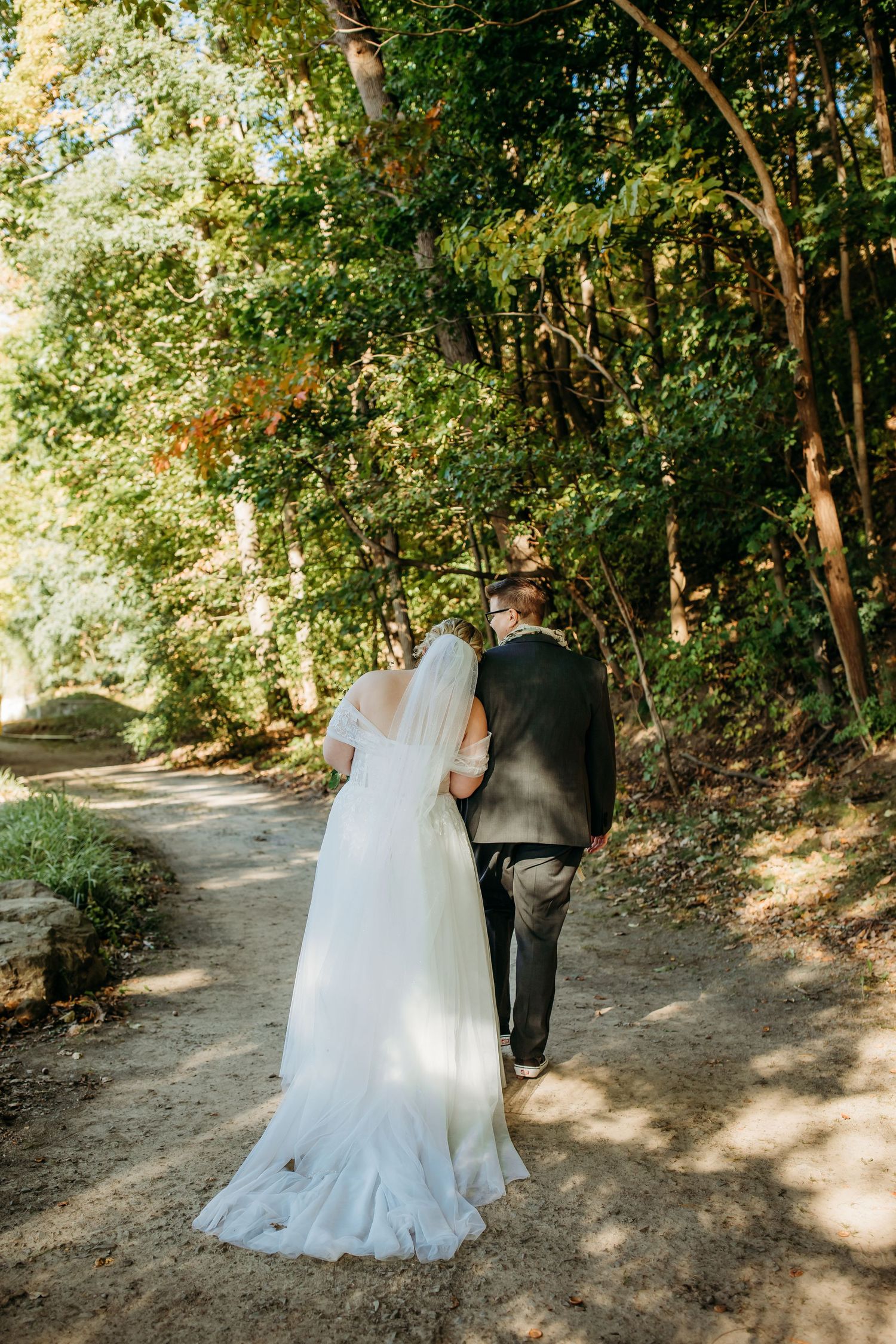 Cindy and Ashley walk back up the aisle after their wedding ceremony. Cindy, wearing a long white dress, leans her head on Ashley's shoulder