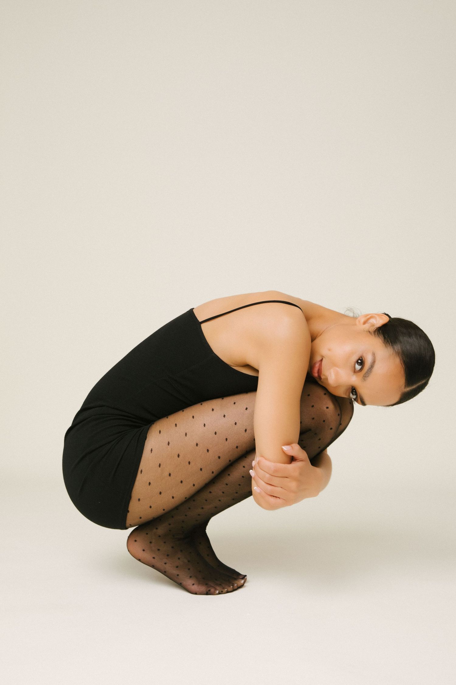 Editorial fashion model portfolio portrait of black woman hugging knees in tights at Santa Monica studio by LA photography Phia Photography.