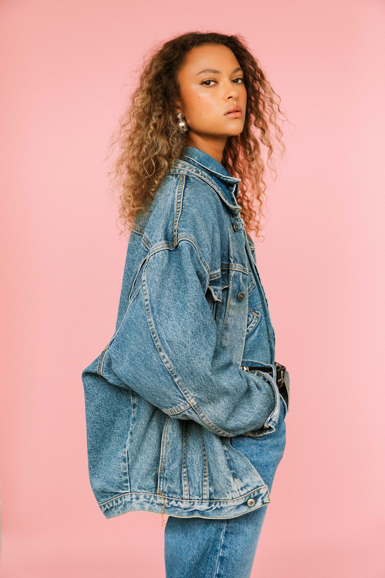 Editorial model portfolio portrait of Black woman styled in denim outfit with pink backdrop at Santa Monica studio by Phia Photography.