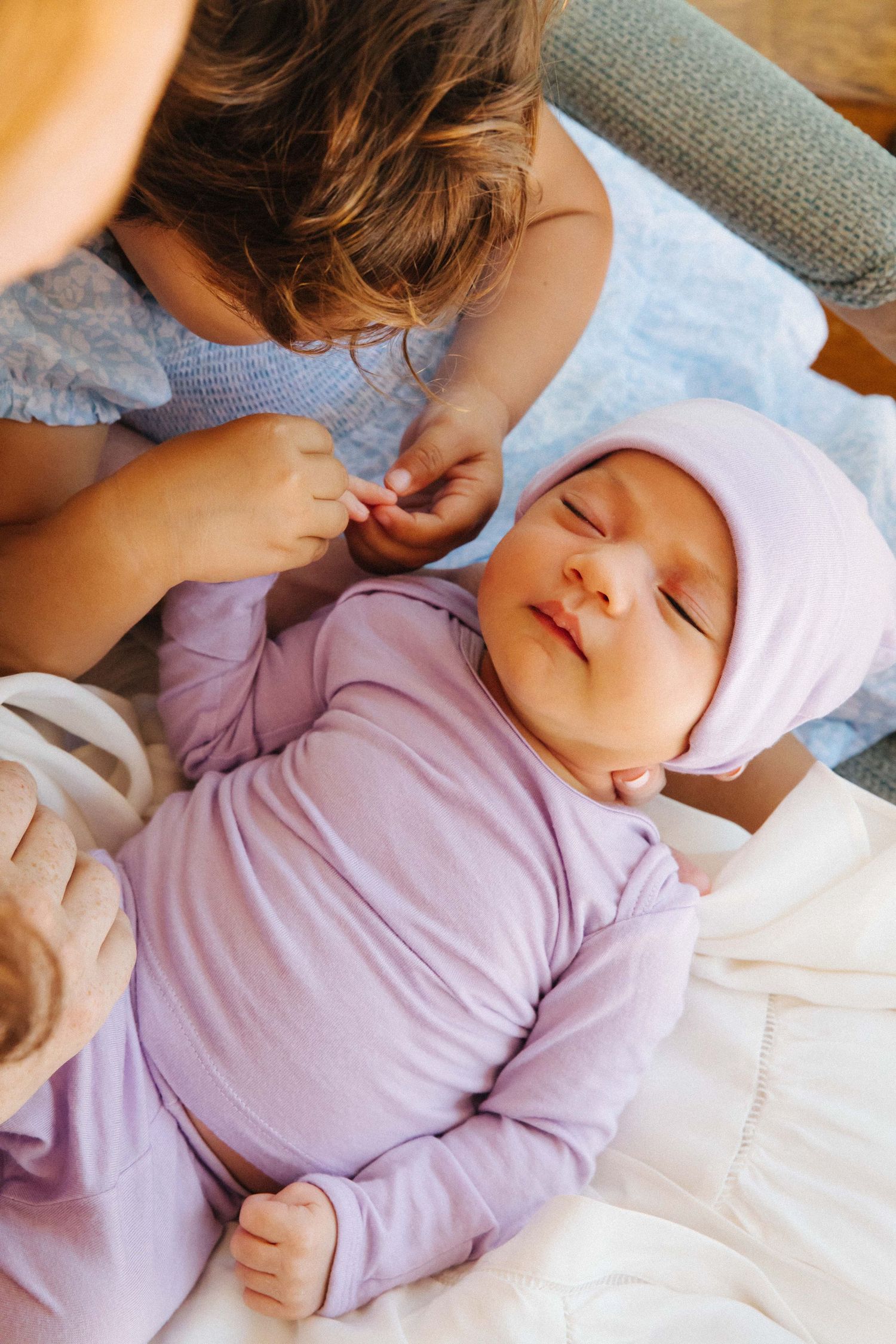 Milestone moment: sibling holding newborn baby sister, in-home newborn photography Santa Monica by photographer Phia Photography