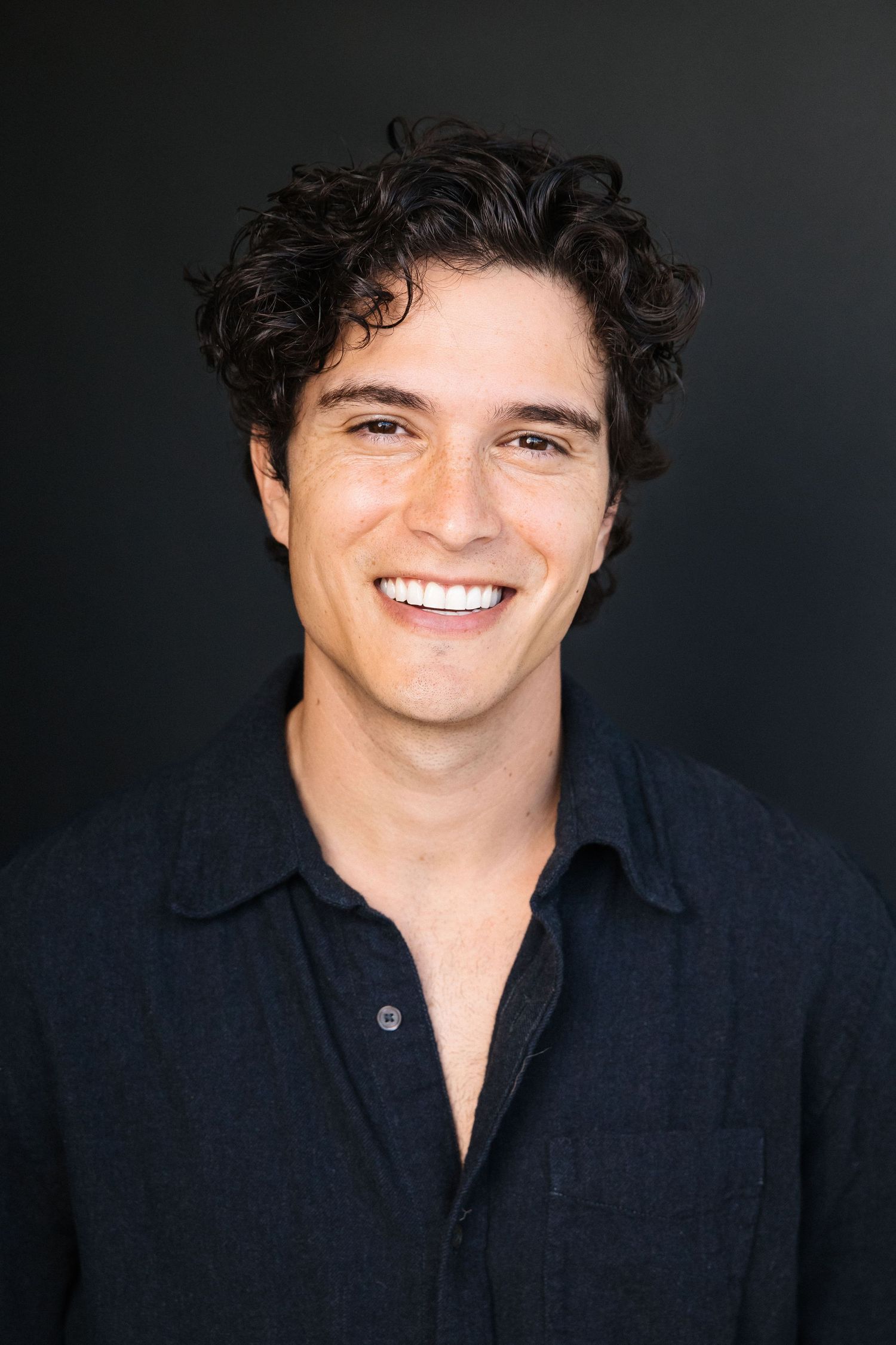Cinematic actor headshot of a happy man with a dark backdrop at a professional Santa Monica studio shot by Phia Photography.
