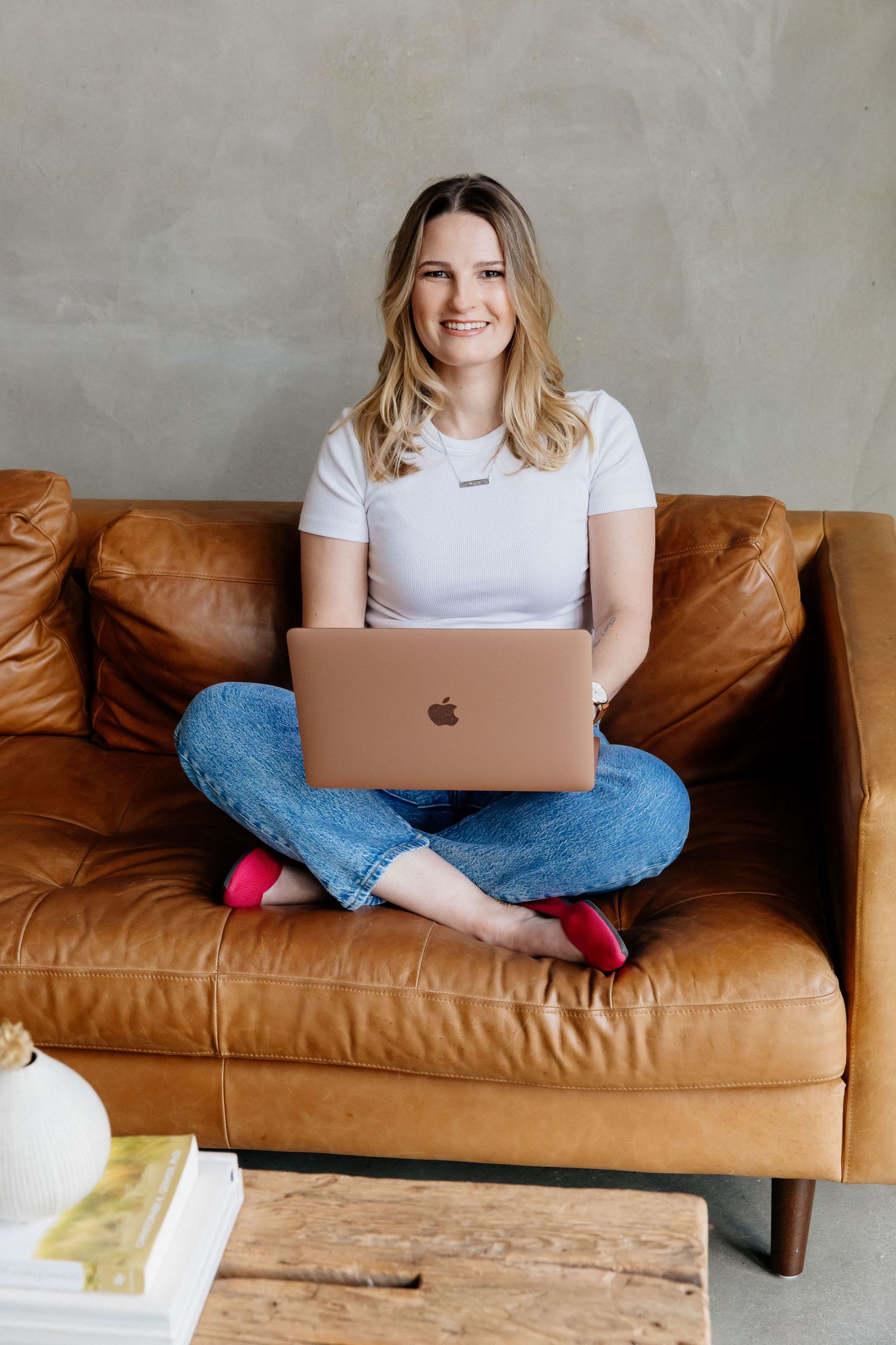 Creative woman smiling with laptop on couch during natural light personal branding session with Los Angeles photographer Phia Photography.