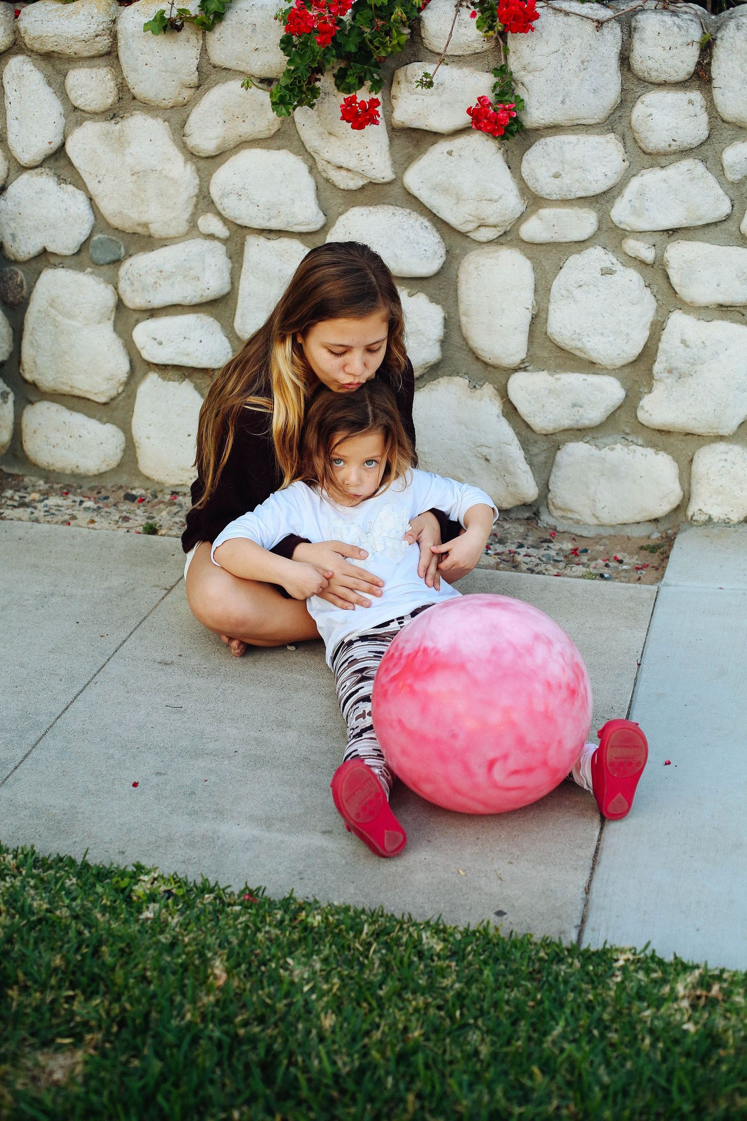 Two sisters sitting together outside, children's portrait photography Santa Monica by photographer Phia Photography