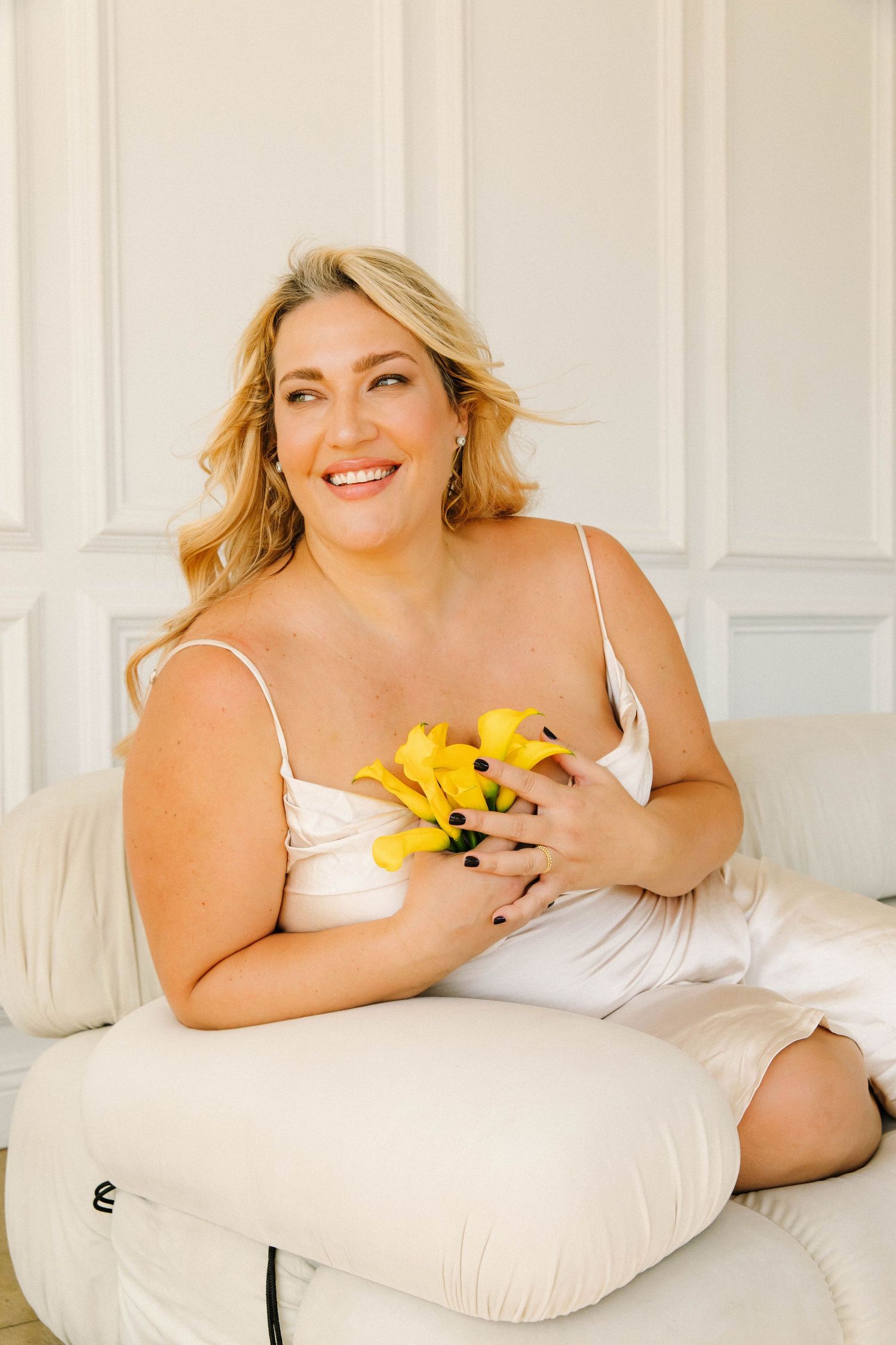 Lifestyle branding portrait of professional LA woman smiling with yellow flowers in Los Angeles studio by Phia Photography.