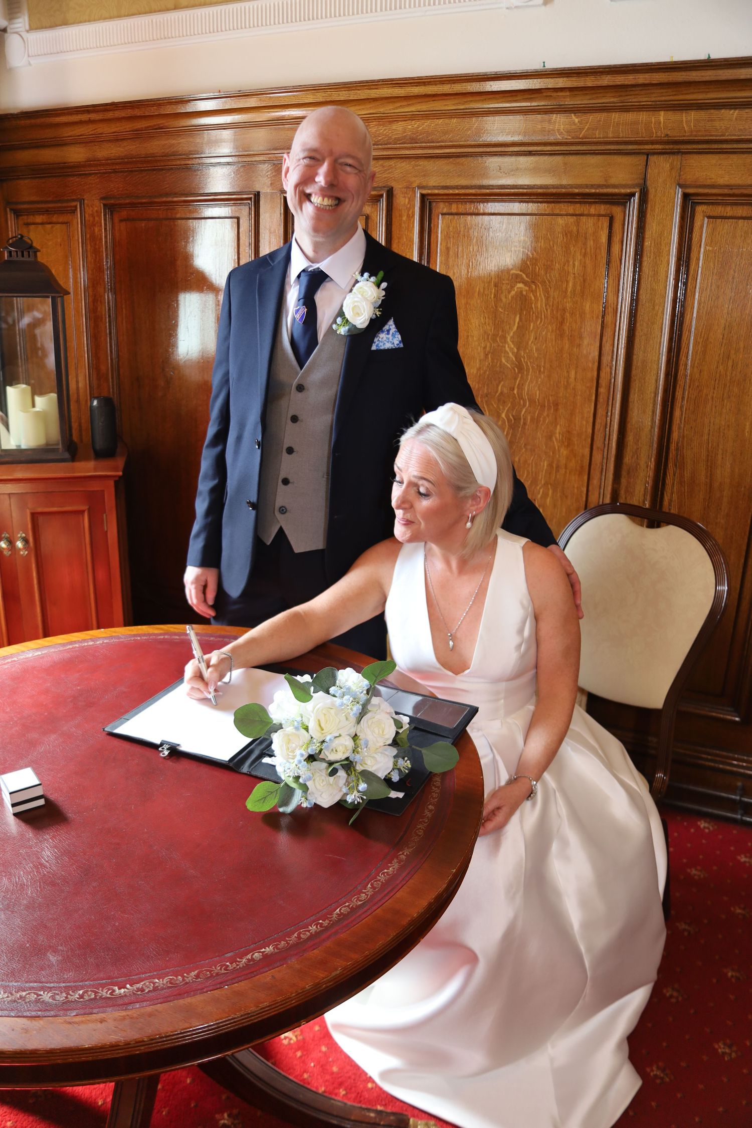 A sequence of photos showing a bride in a white dress signing documents at a round table with a red top.