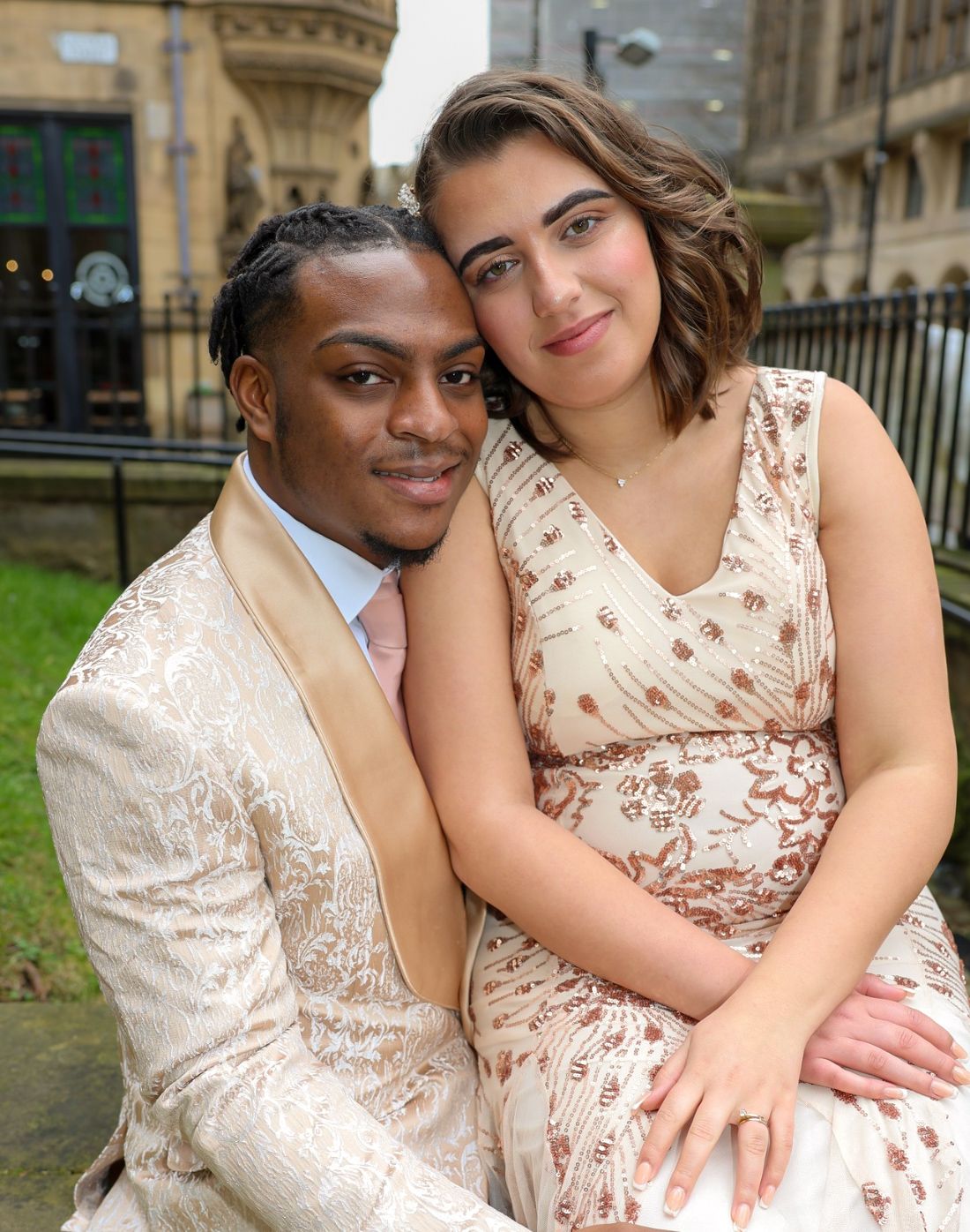 A couple in matching cream outfits embrace outdoors in a romantic photoshoot series.
