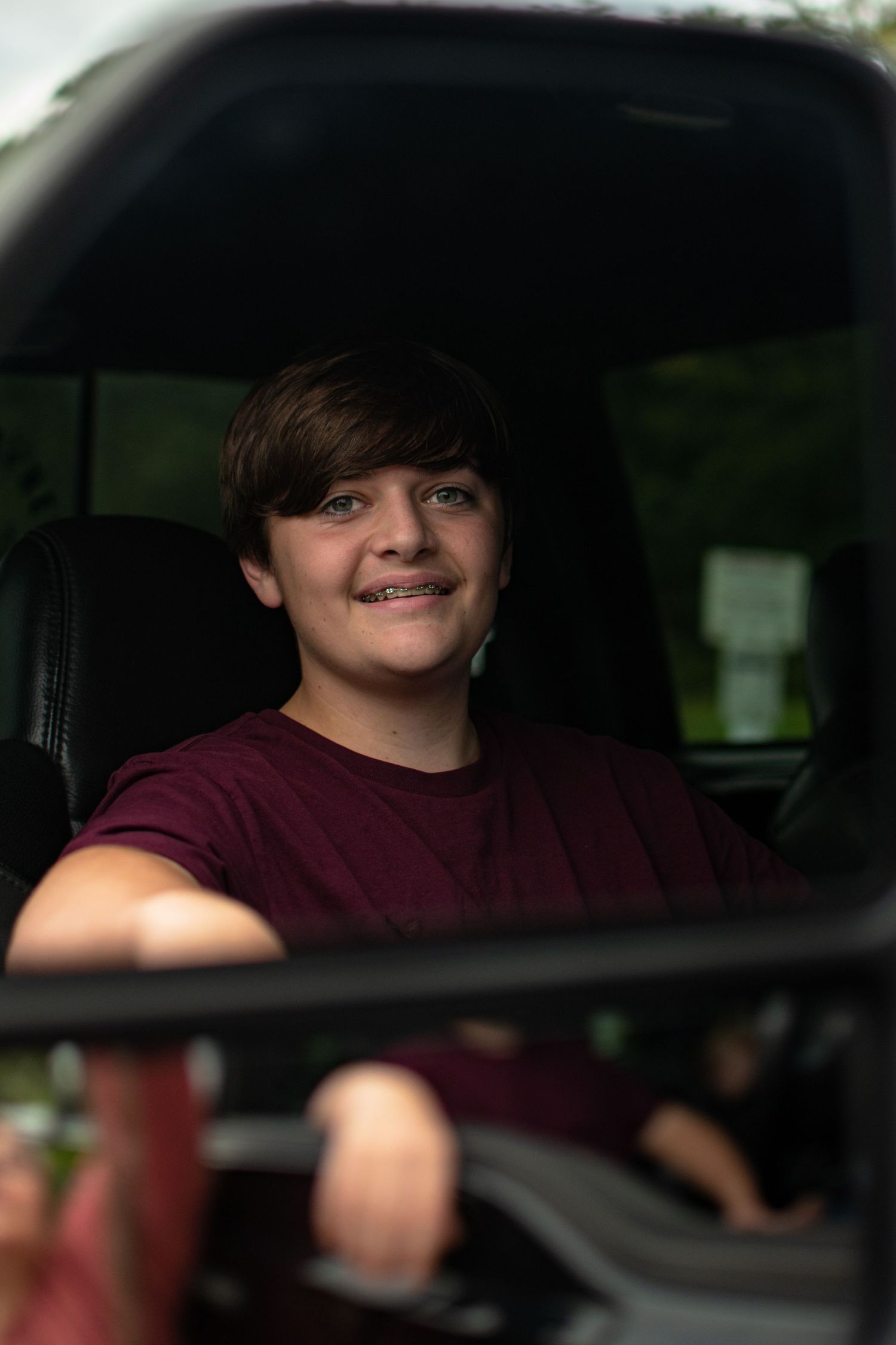 High school guy in black truck, photo take in side mirror of smiling guy with braces. At Millstone Landing in Hardeeville, South Carolina
