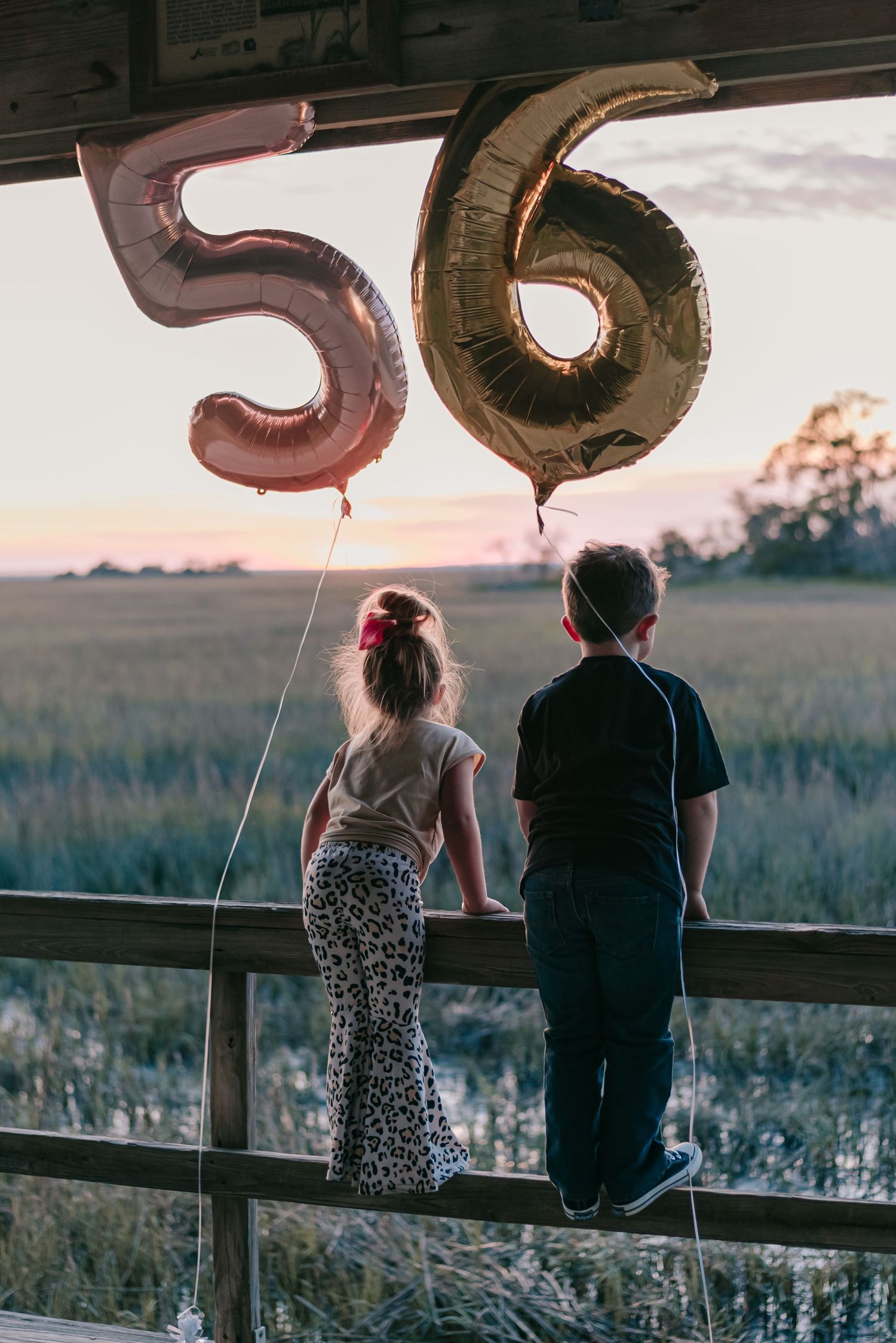 little girl and little boy pictured looked at a sunset with 5 and 6 birthday balloons floating above them at  Hunting Island, South Carolina