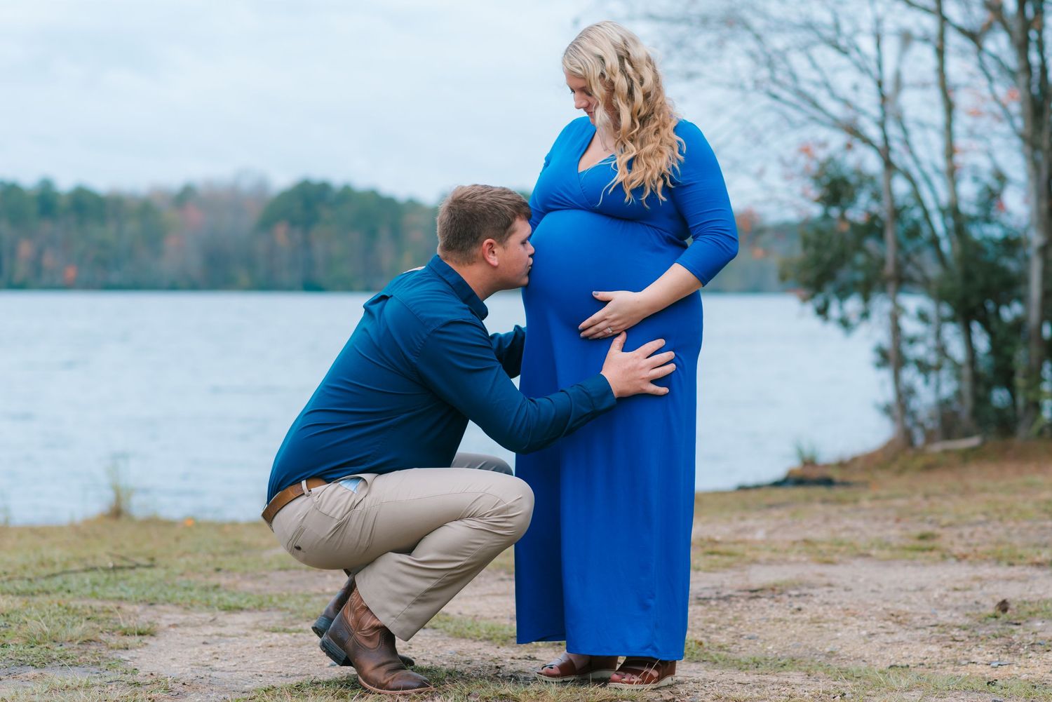 Dad kissing mom's baby belly at Lake Warren in Hampton, SC. Lake Warren in the background.