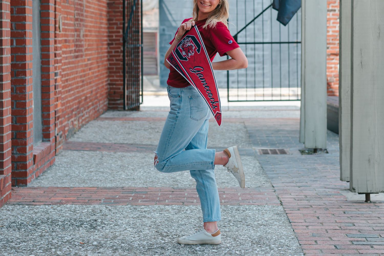 High school senior girl wearing South Carolina Gamecocks shirt holding University of South Carolina pennant in downtown Walterboro, SC.