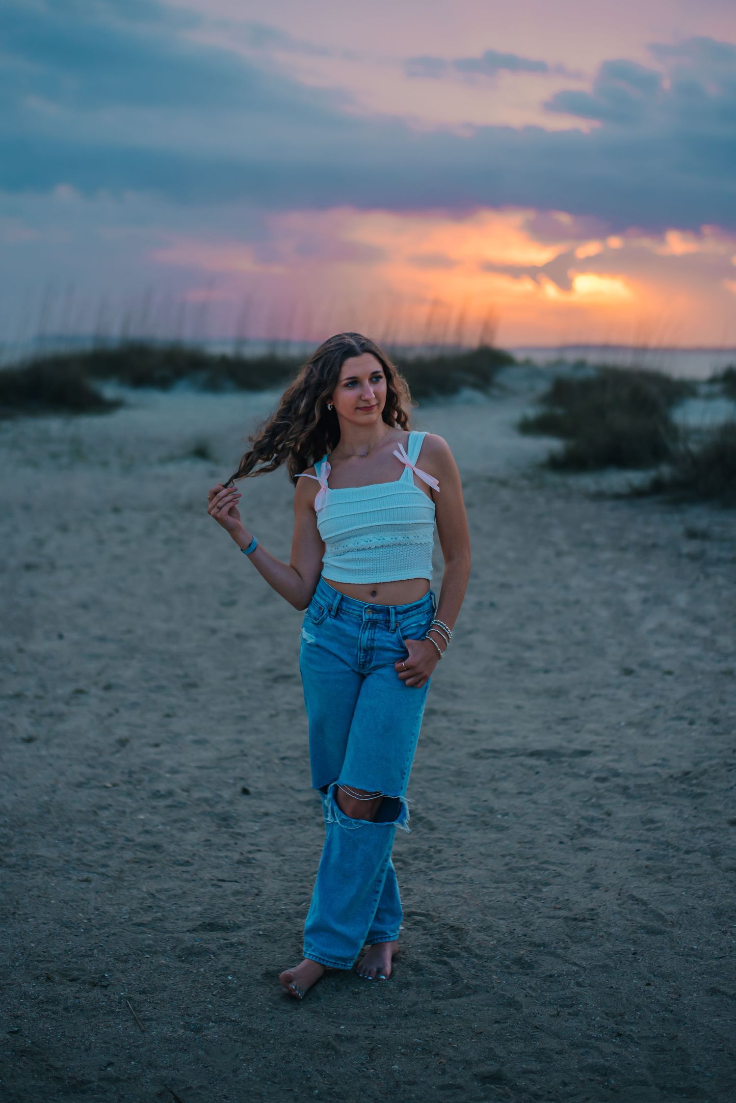 High school senior girl at Edisto beach in front of watercolor sunset sky. Edisto Island, South Carolina