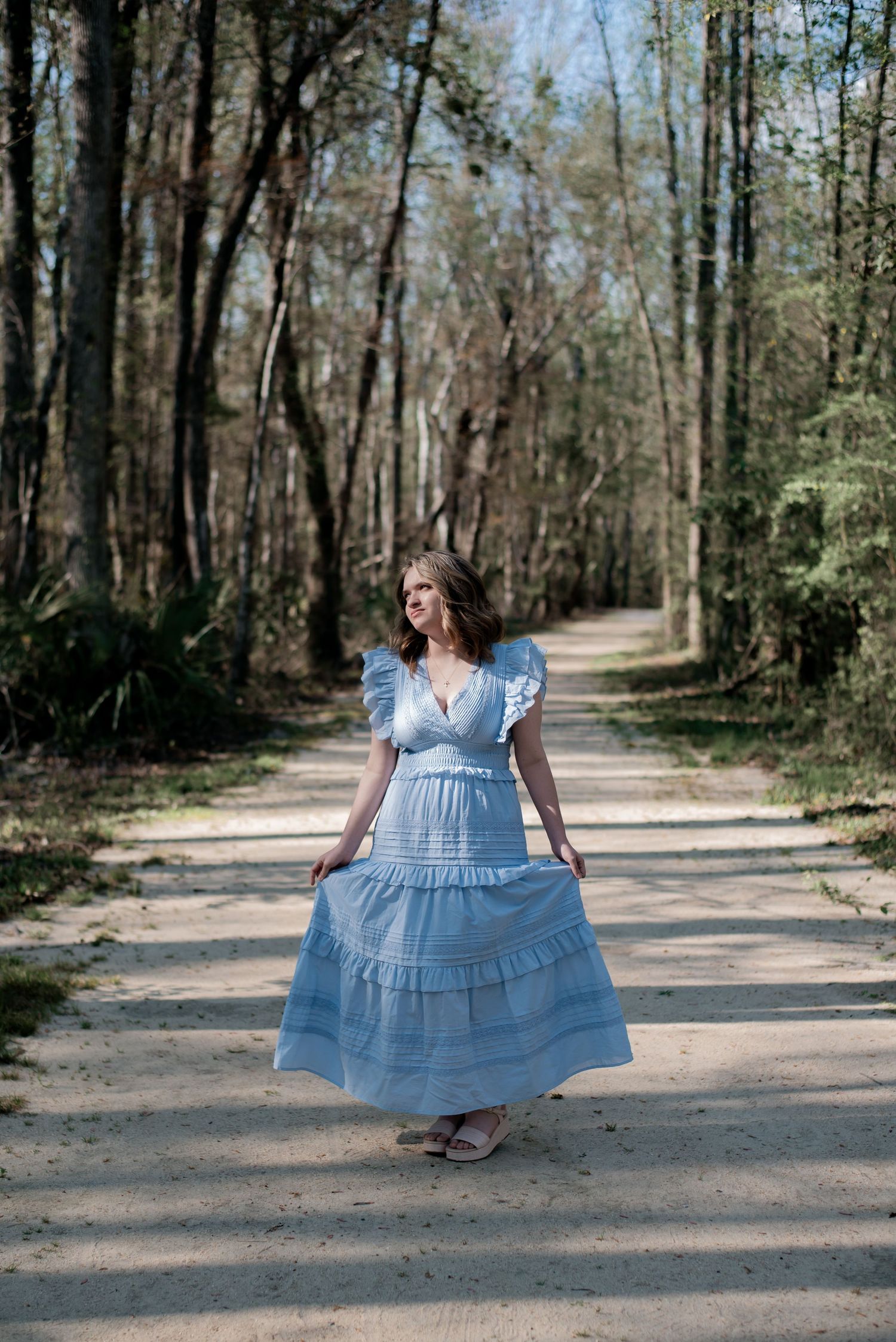 High school senior girl on dirt pathway at Walterboro Wildlife Sanctuary nature trail in Colleton County, Walterboro, South Carolina
