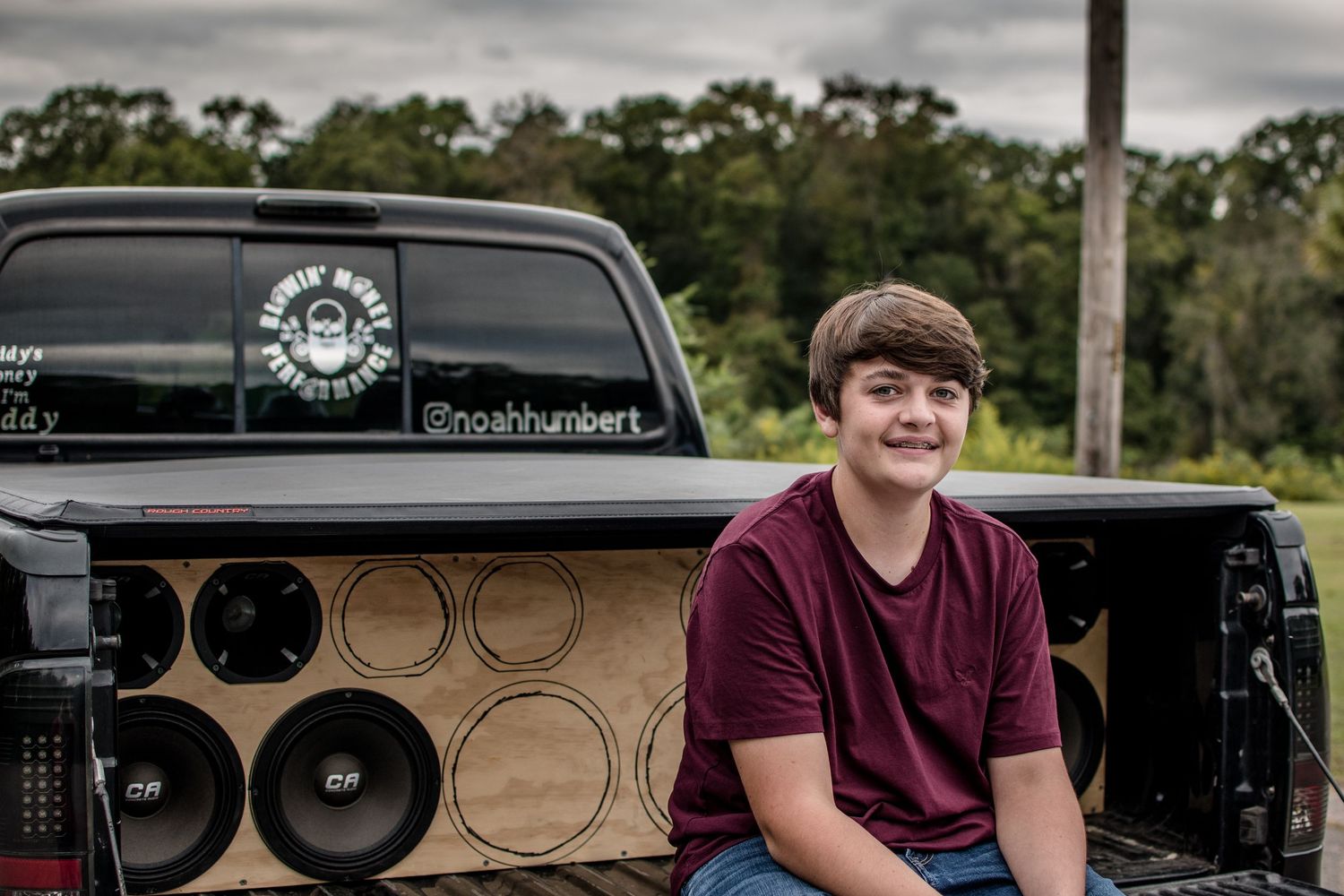 High school senior guy sitting on truck tailgate in front of speakers at Millstone Landing in Hardeeville, South Carolina.