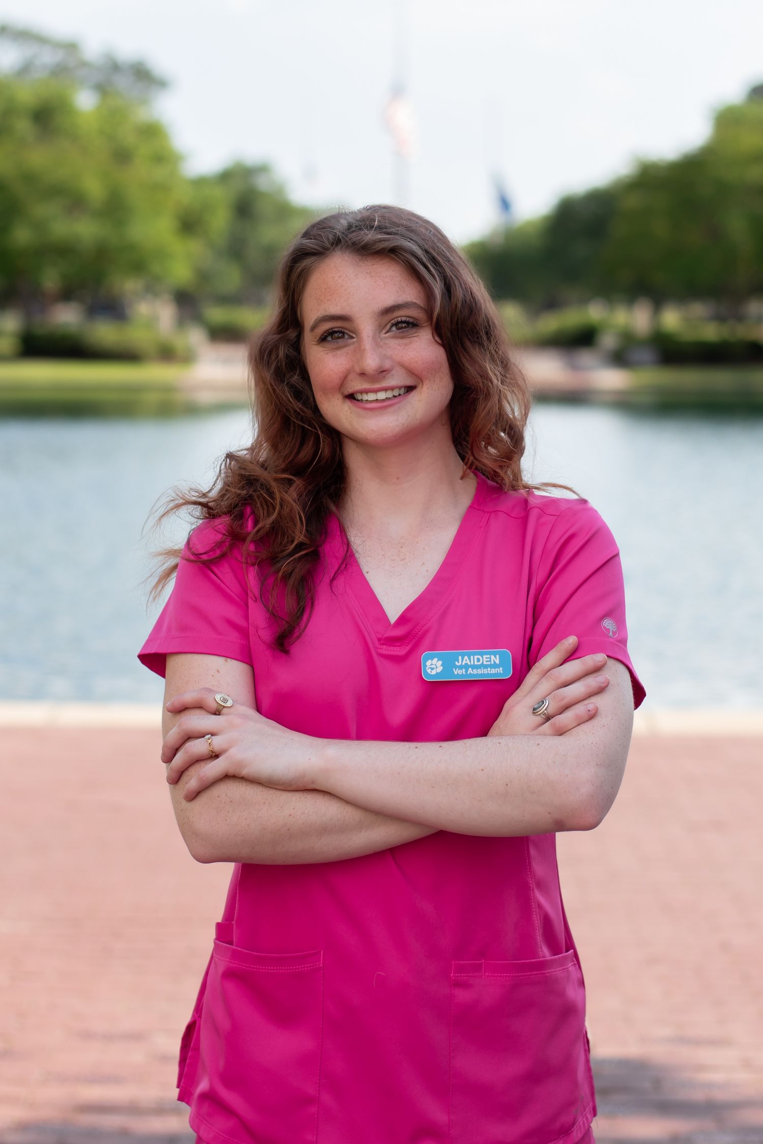 Charleston Southern senior graduate wearing pink scrubs in front of fountain on campus in Charleston, South Carolina.