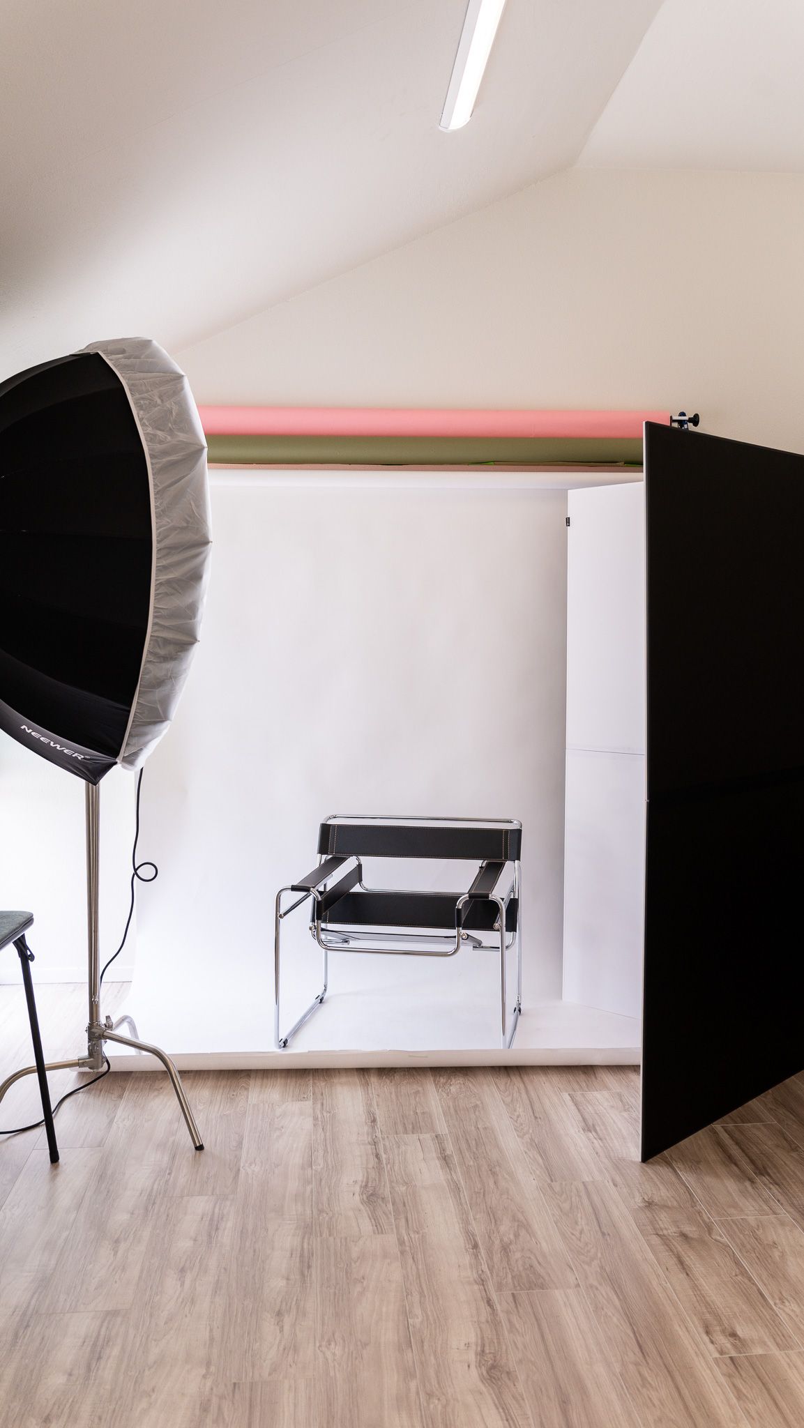 Photography studio setup with softbox light and white backdrop featuring modern chair.