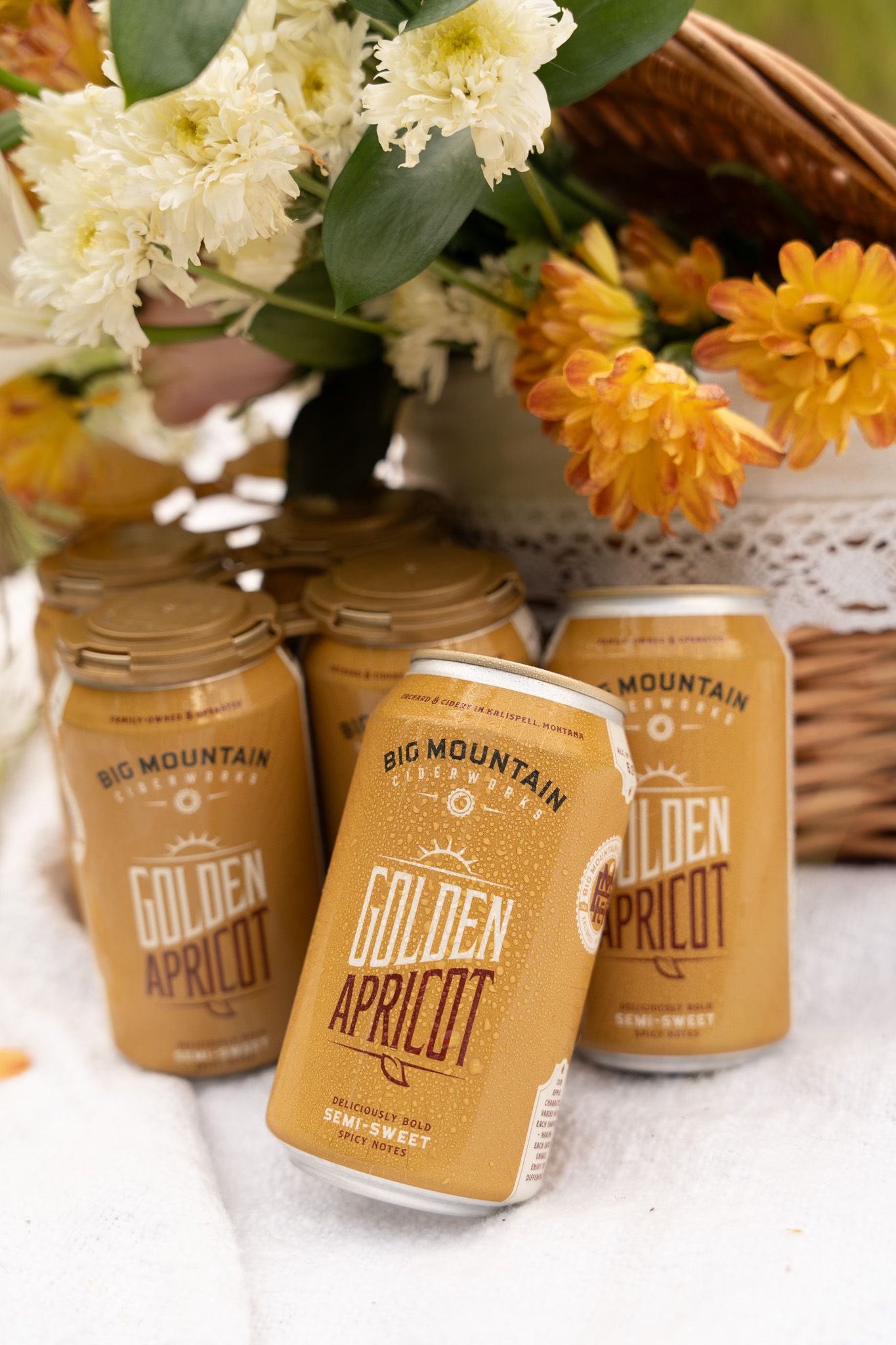 Multiple jars with Big Mountain Golden Apricot labels displayed on a white surface with white and yellow flowers.