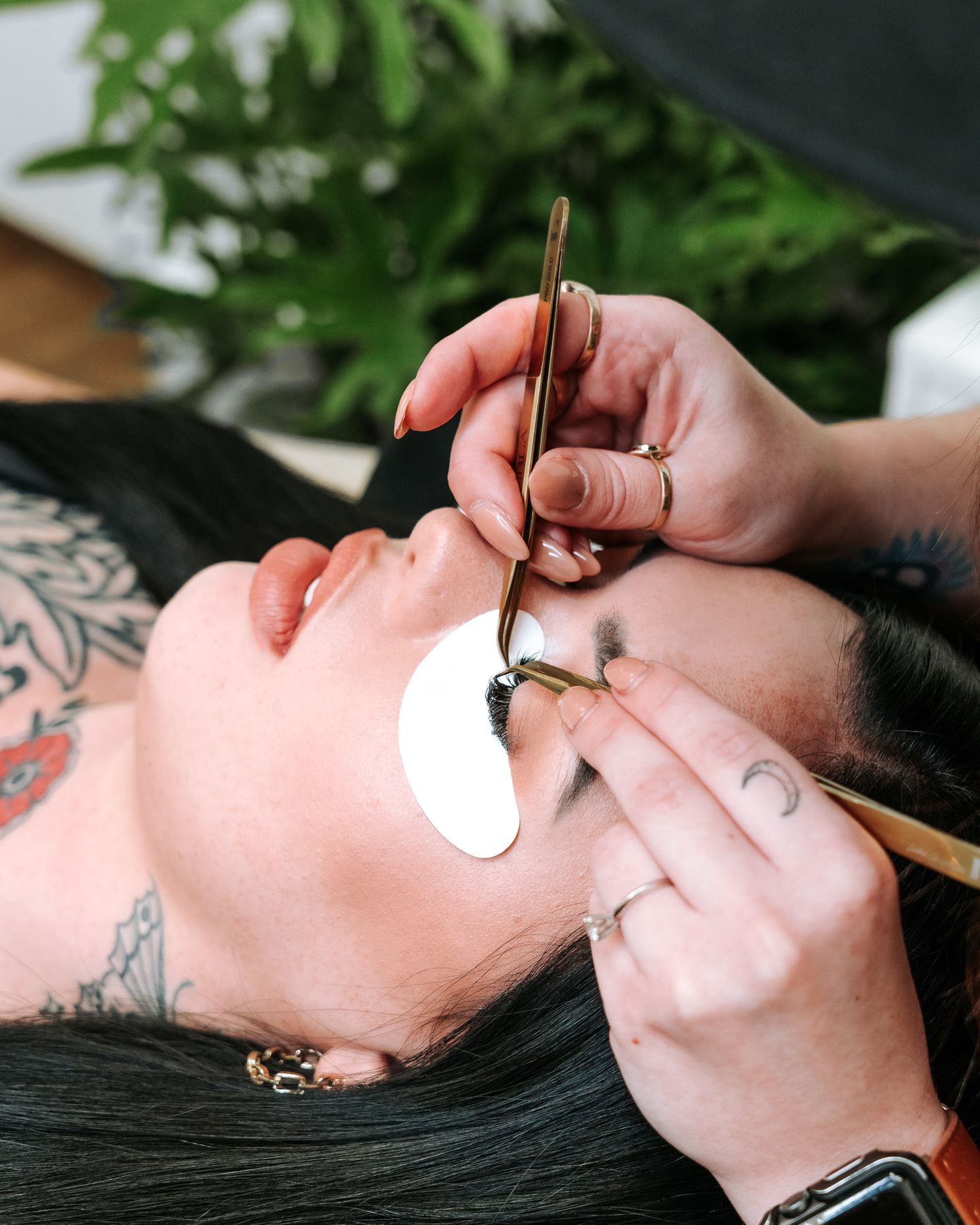 Close-up of eyelash extension procedure with protective under-eye pads.
