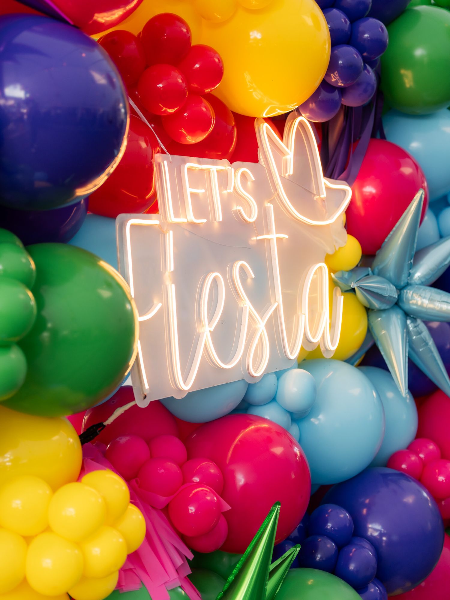 Vibrant balloon arch with neon 'Let's Fiesta' sign surrounded by colorful balloons.