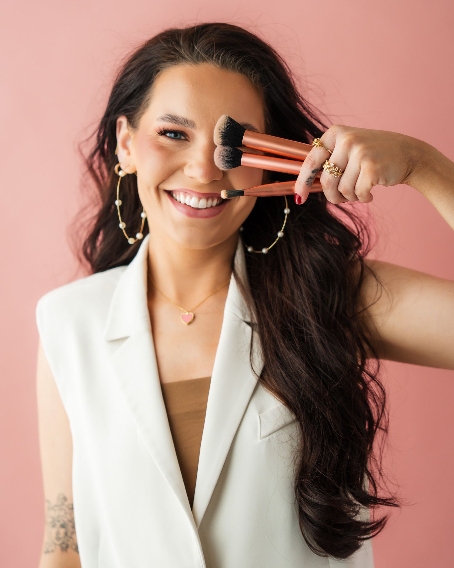 Professional headshots against a pink background showing confident poses in a white blazer.