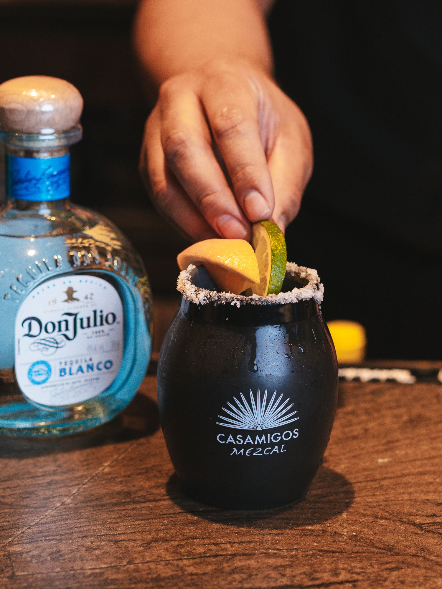Margaritas in black ceramic cups with salt rims and Casamigos tequila bottles.
