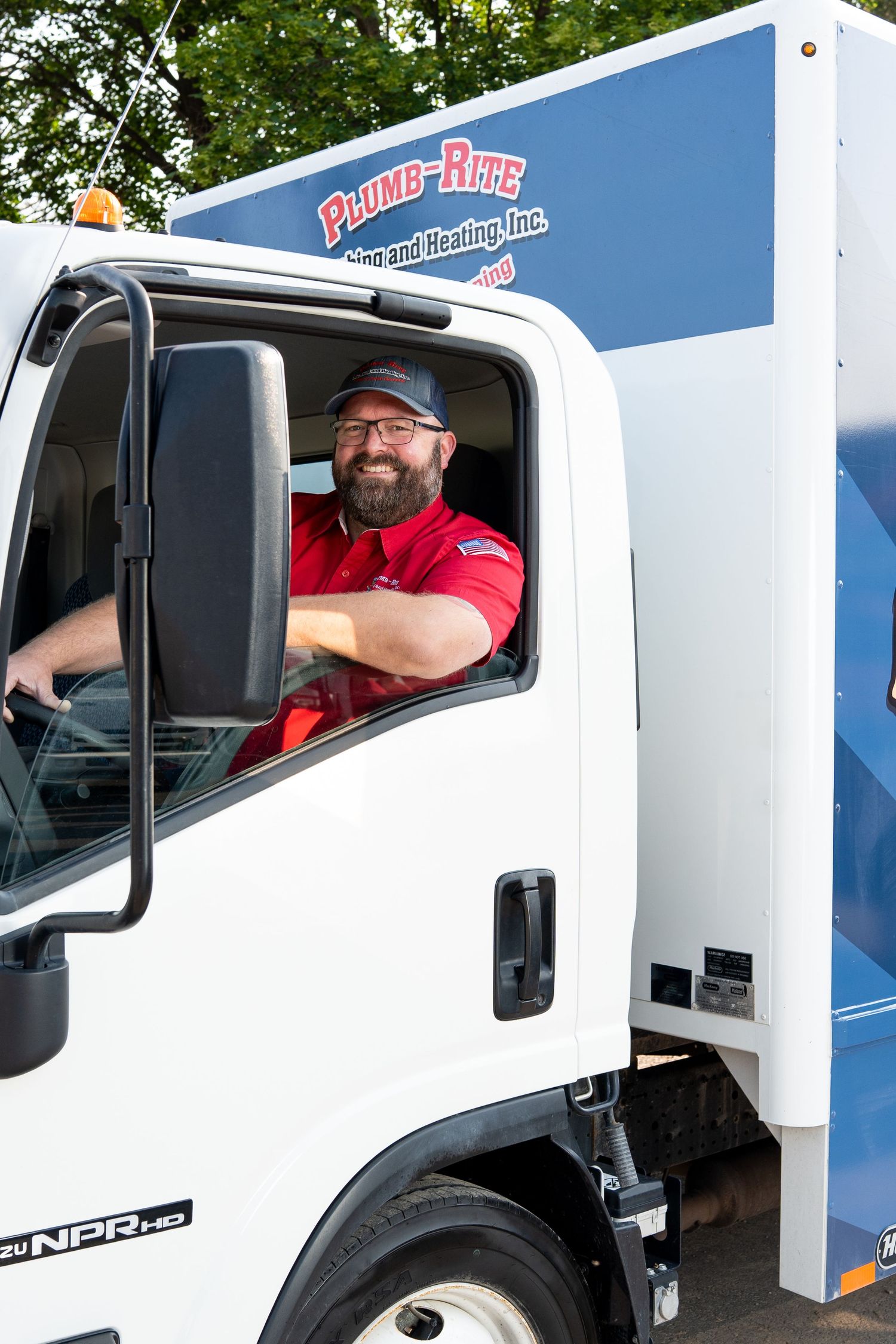 Delivery driver smiling from the window of a white moving truck.