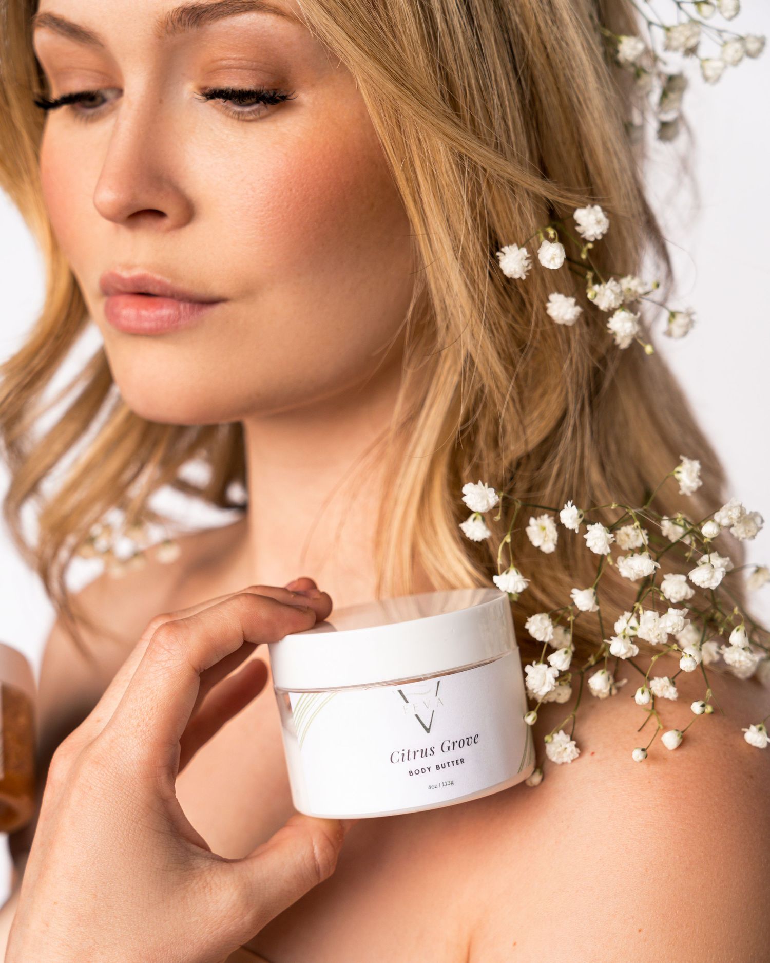 Artistic beauty shot with delicate baby's breath flowers and white product packaging.
