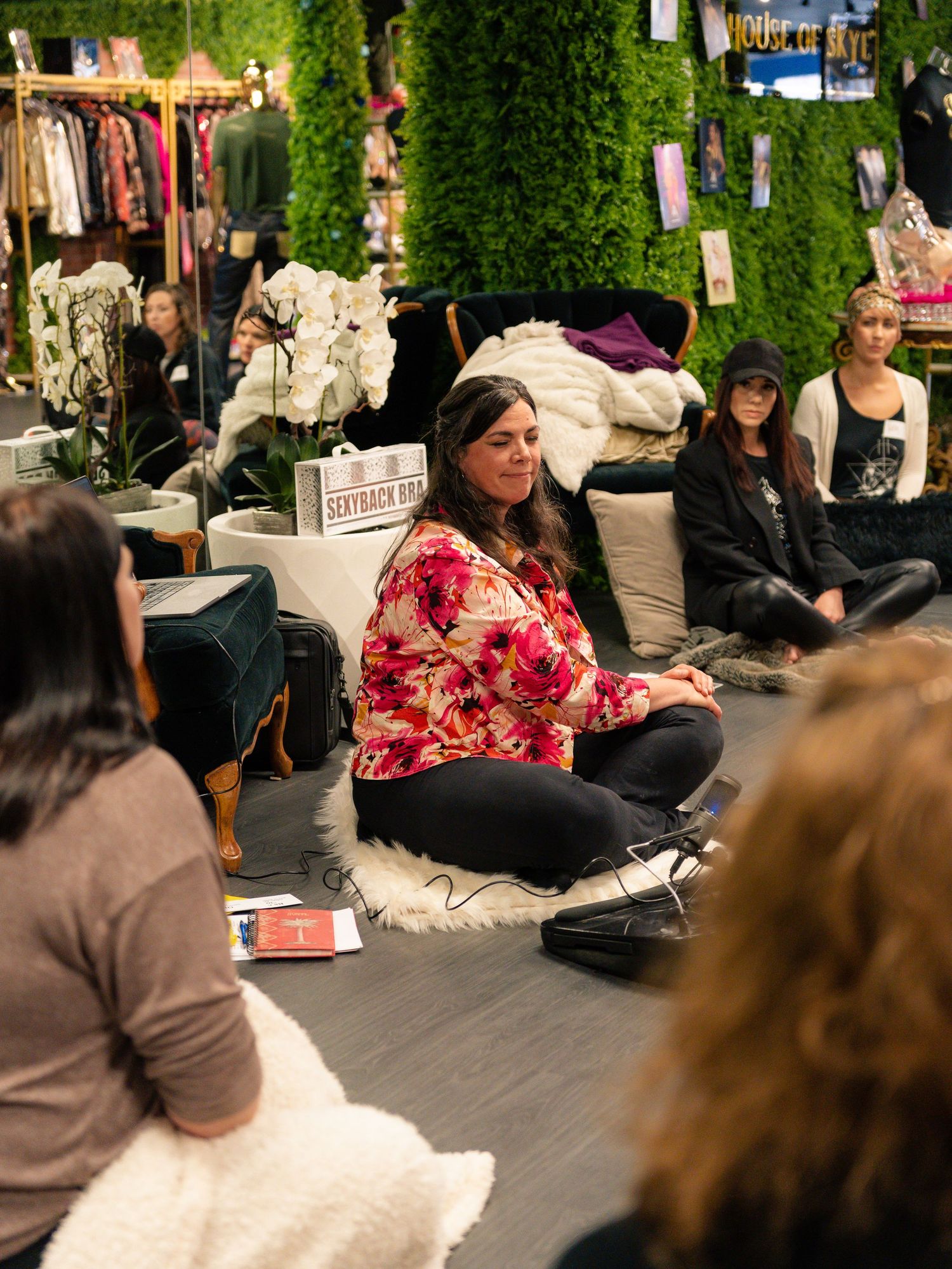 Group gathering in retail space with green wall backdrop and clothing racks.