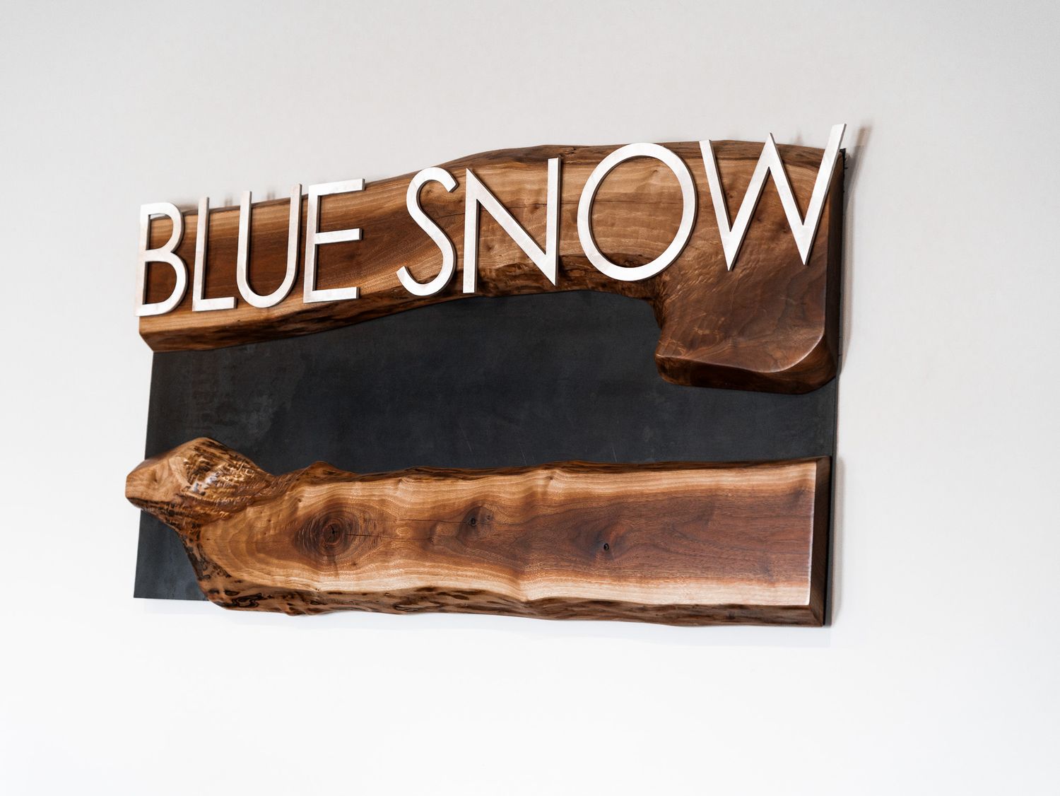 Four brown and white signs are mounted on a light colored wall, with text appearing to be shop or business signage.