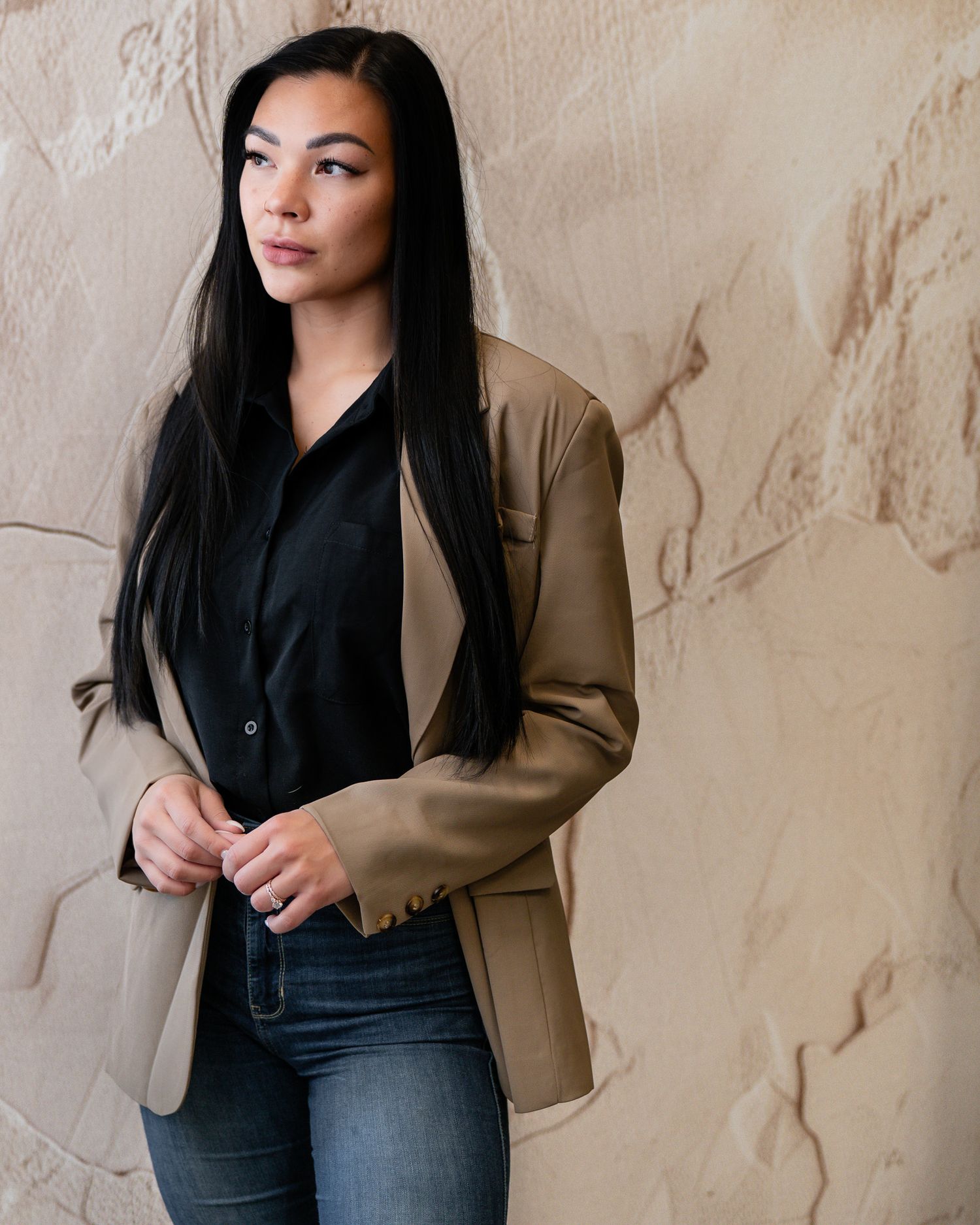 Fashion portrait series featuring black shirt and tan blazer against textured beige wall.