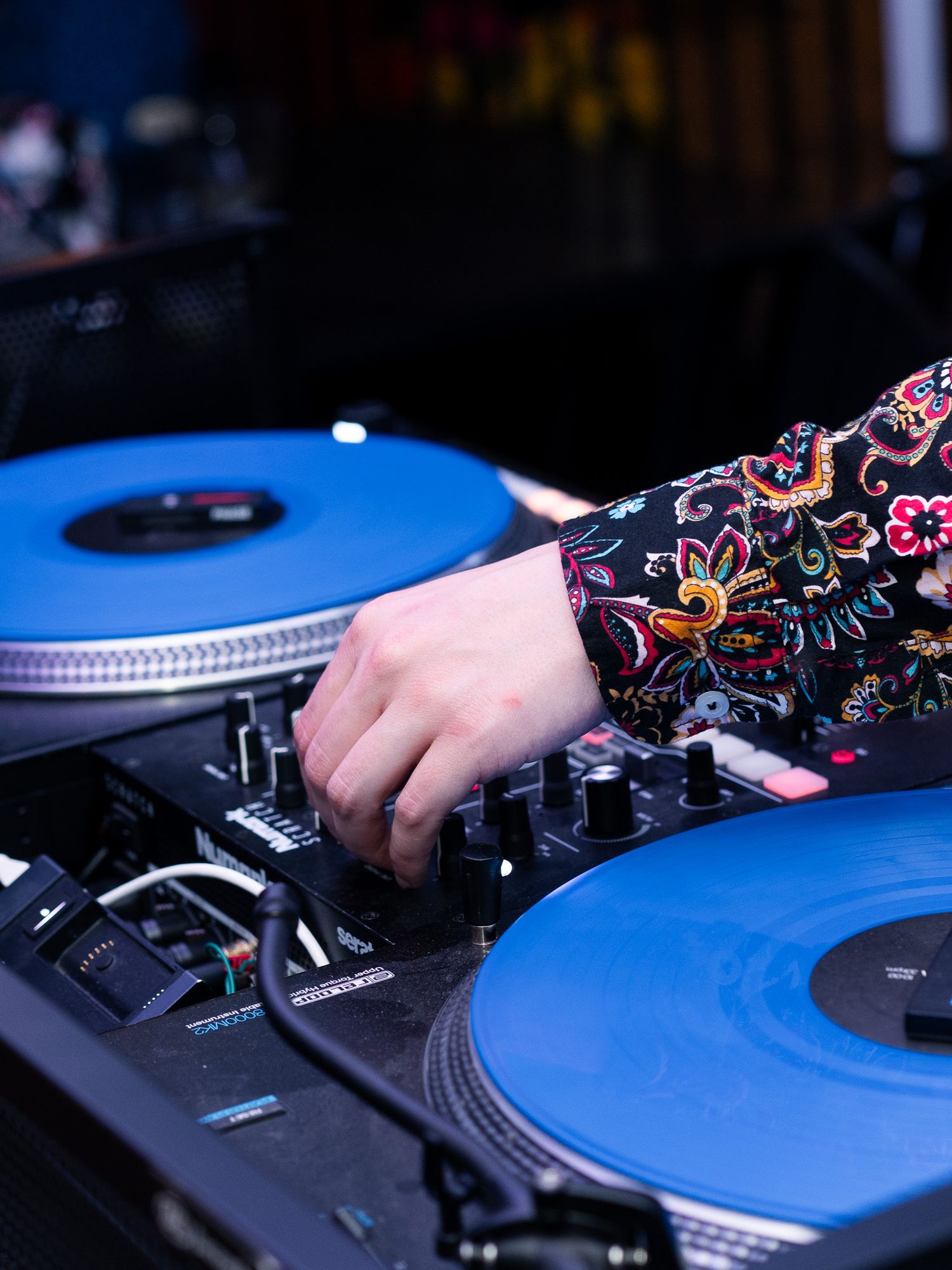 Close-up of DJ mixing on turntables with blue vinyl records.