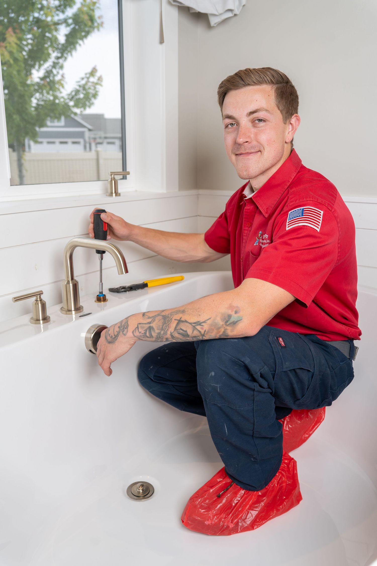 Professional plumber in red uniform working on bathroom sink installation.