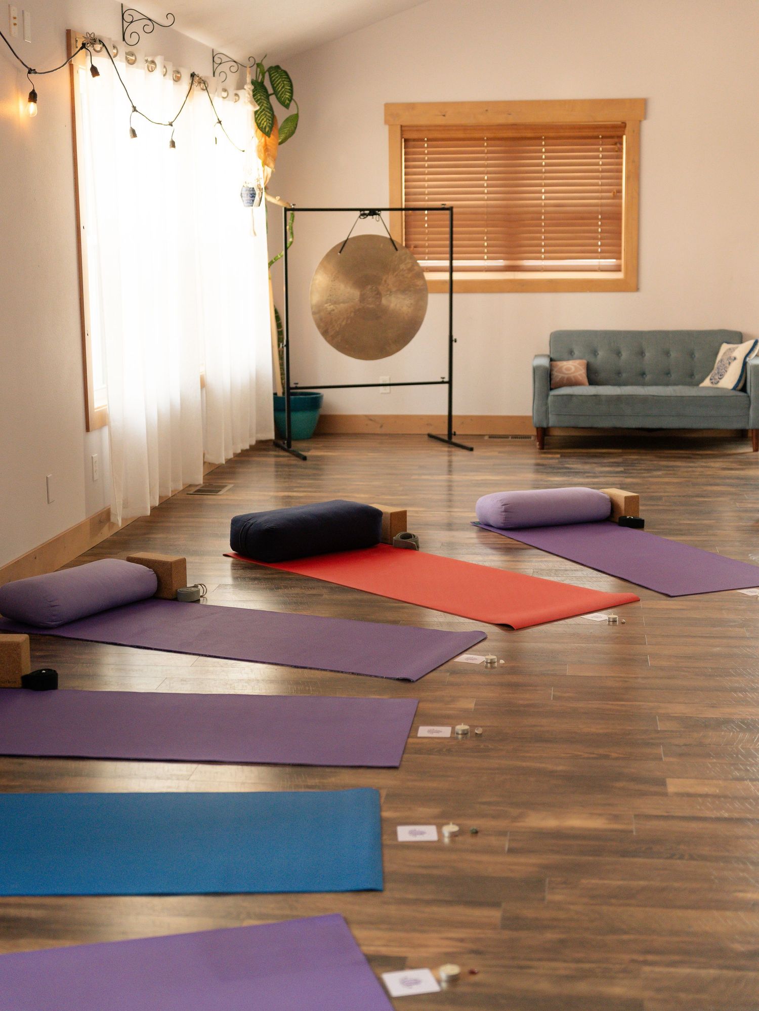 Yoga studio interior with purple and red exercise mats laid out on wooden flooring.