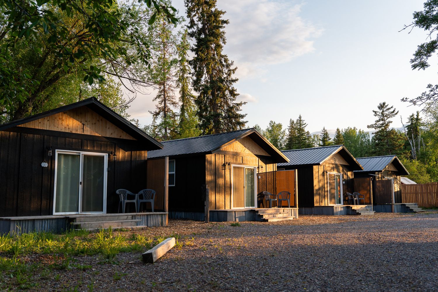 Panoramic view of contemporary vacation cabins arranged along a gravel path surrounded by forest.
