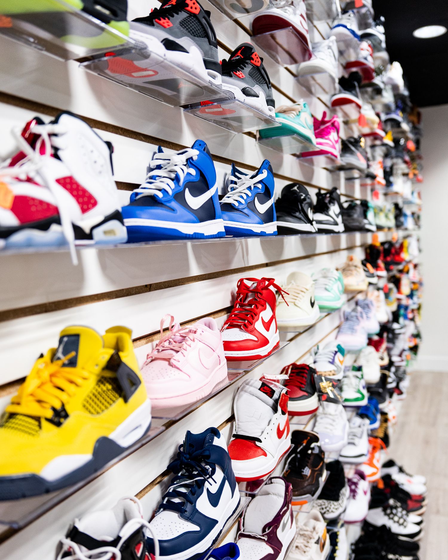 Retail display wall filled with colorful athletic sneakers and sports shoes.