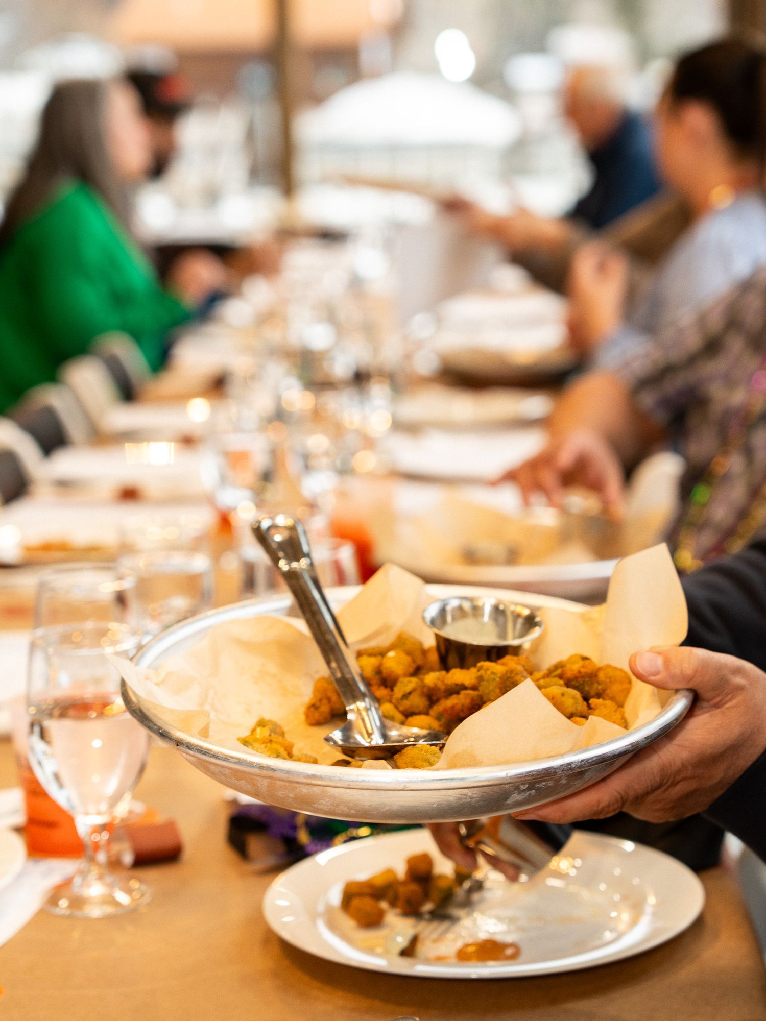 Restaurant dining table with shared plates and wine glasses during group meal service.