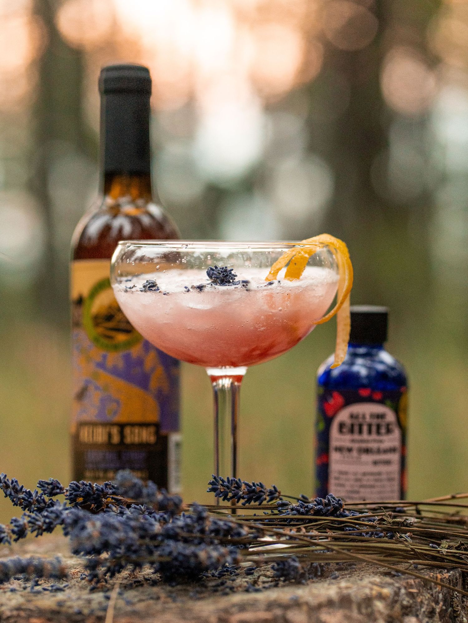 Elegant pink cocktail garnished with orange peel and lavender sprigs in a coupe glass.