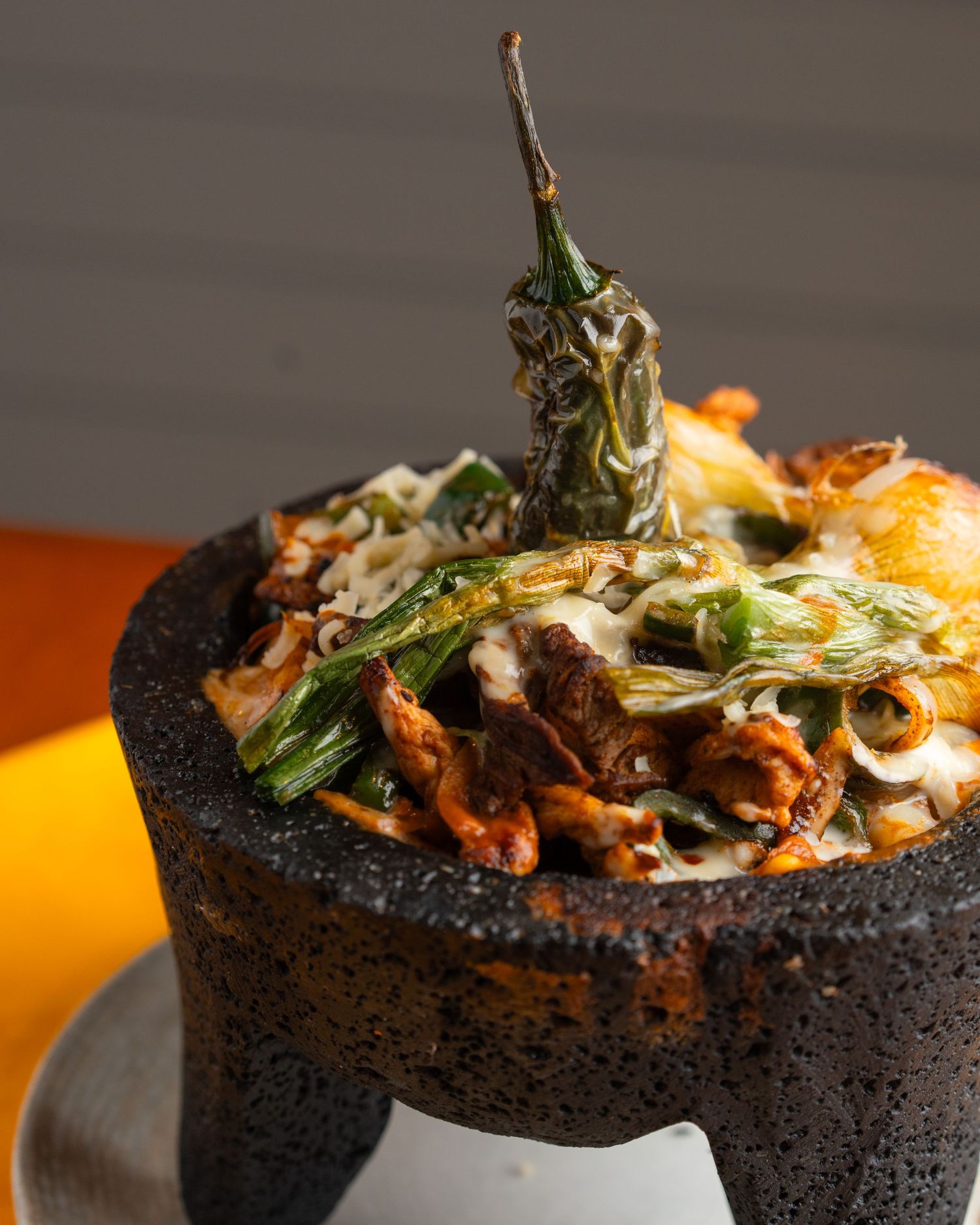 Sizzling Mexican dish served in a traditional molcajete with roasted peppers and melted cheese.