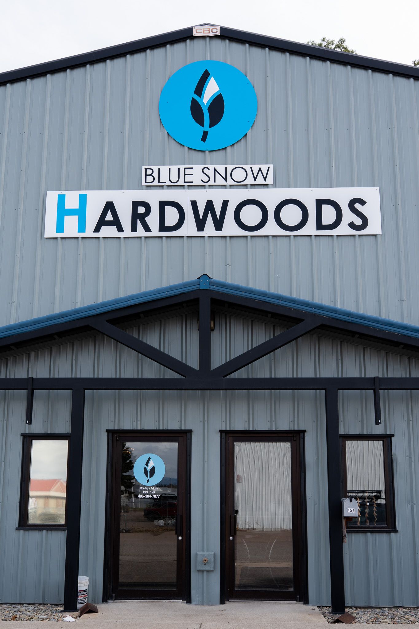 Commercial building exterior with Blue Snow Hardwoods signage and gray metal siding.