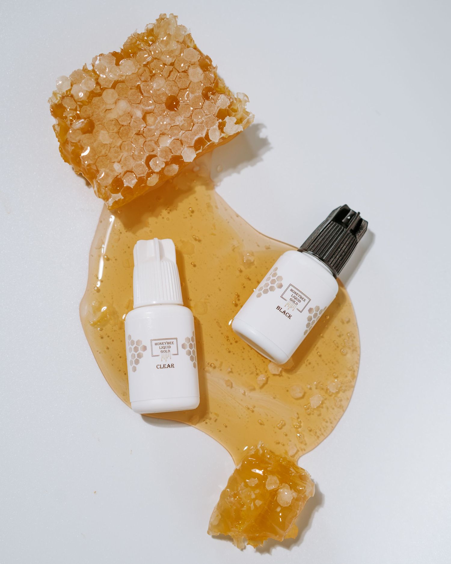 Beauty product bottles arranged with honey crystals on white background.