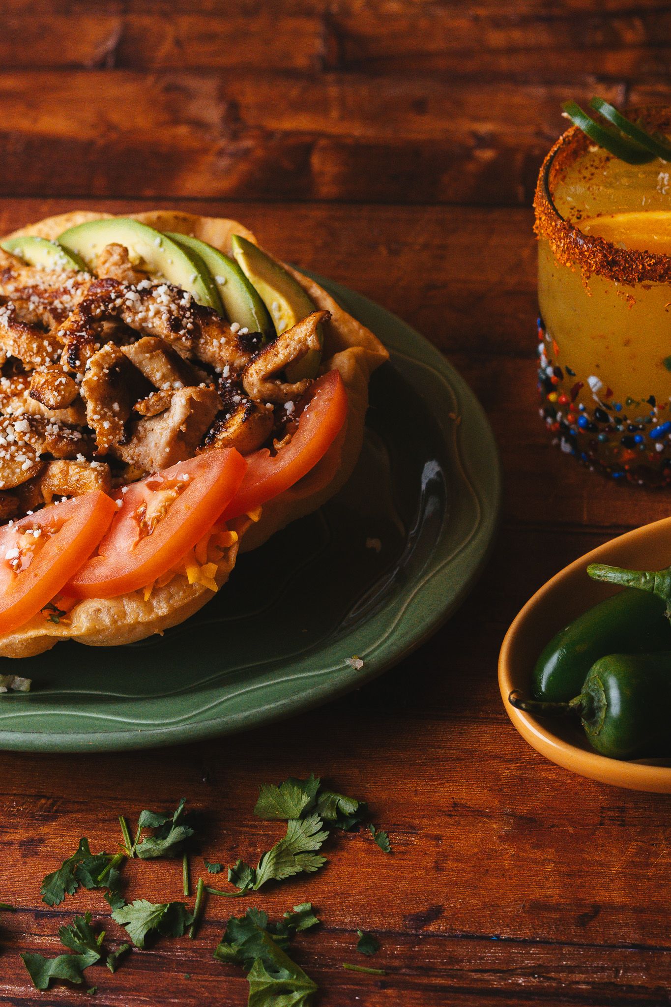 Fresh bagel sandwiches with tomatoes and garnish arranged on green plates.