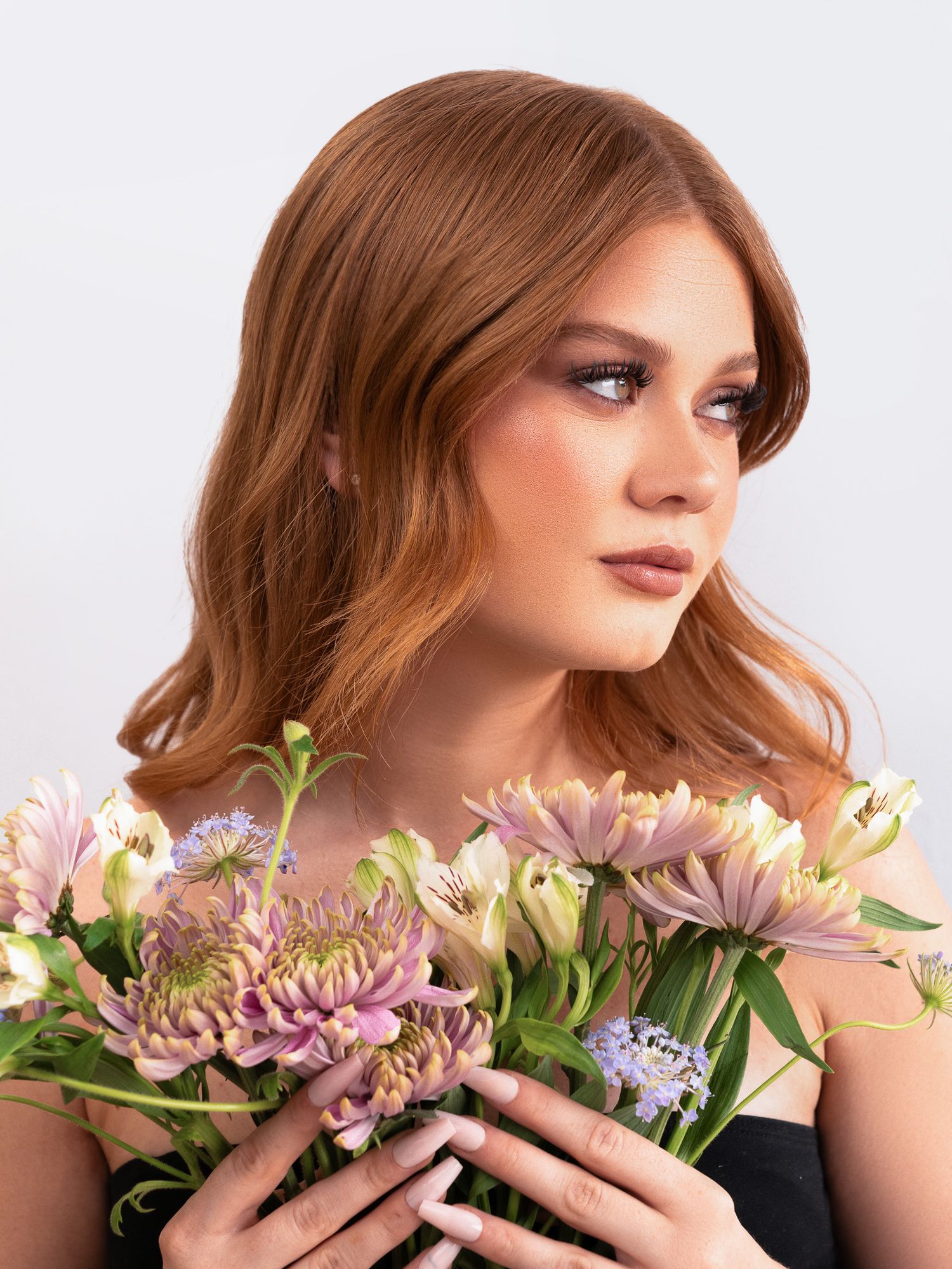 Romantic beauty shot with purple and pink flowers showing soft makeup and styled hair.