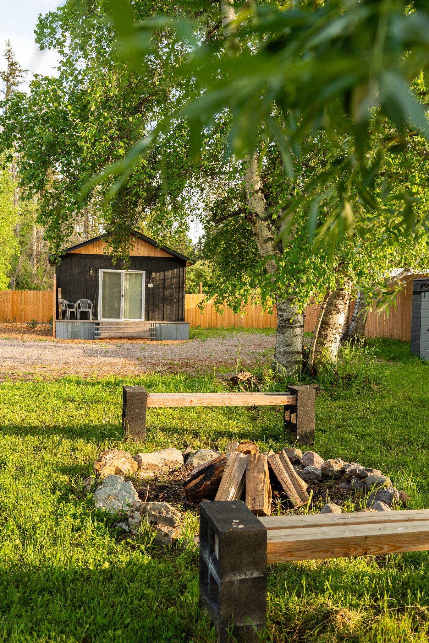 Peaceful backyard scene with green trees and wooden outdoor furniture.