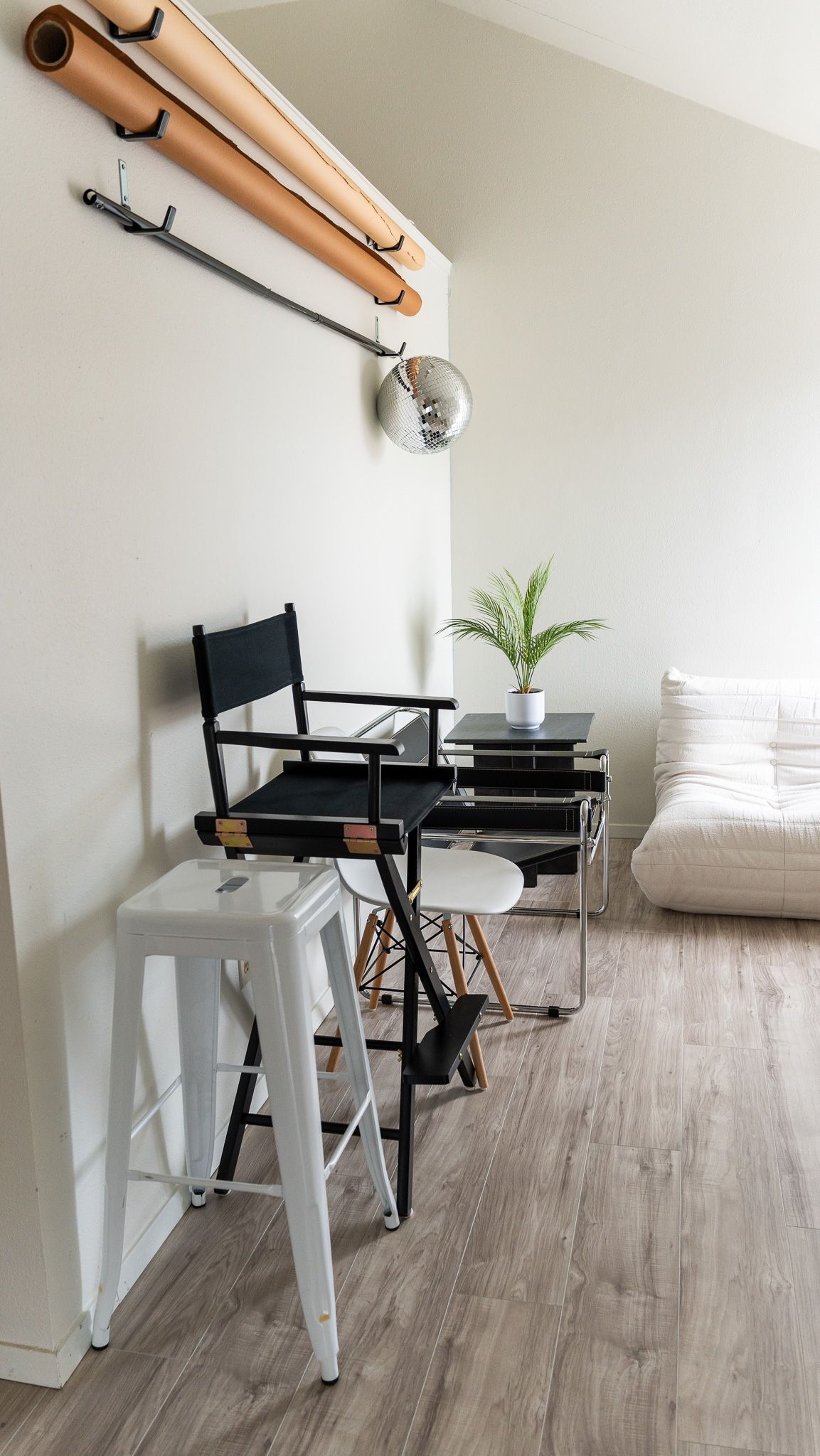 Modern minimalist photography studio space with chairs, white stool and hanging copper tubes.