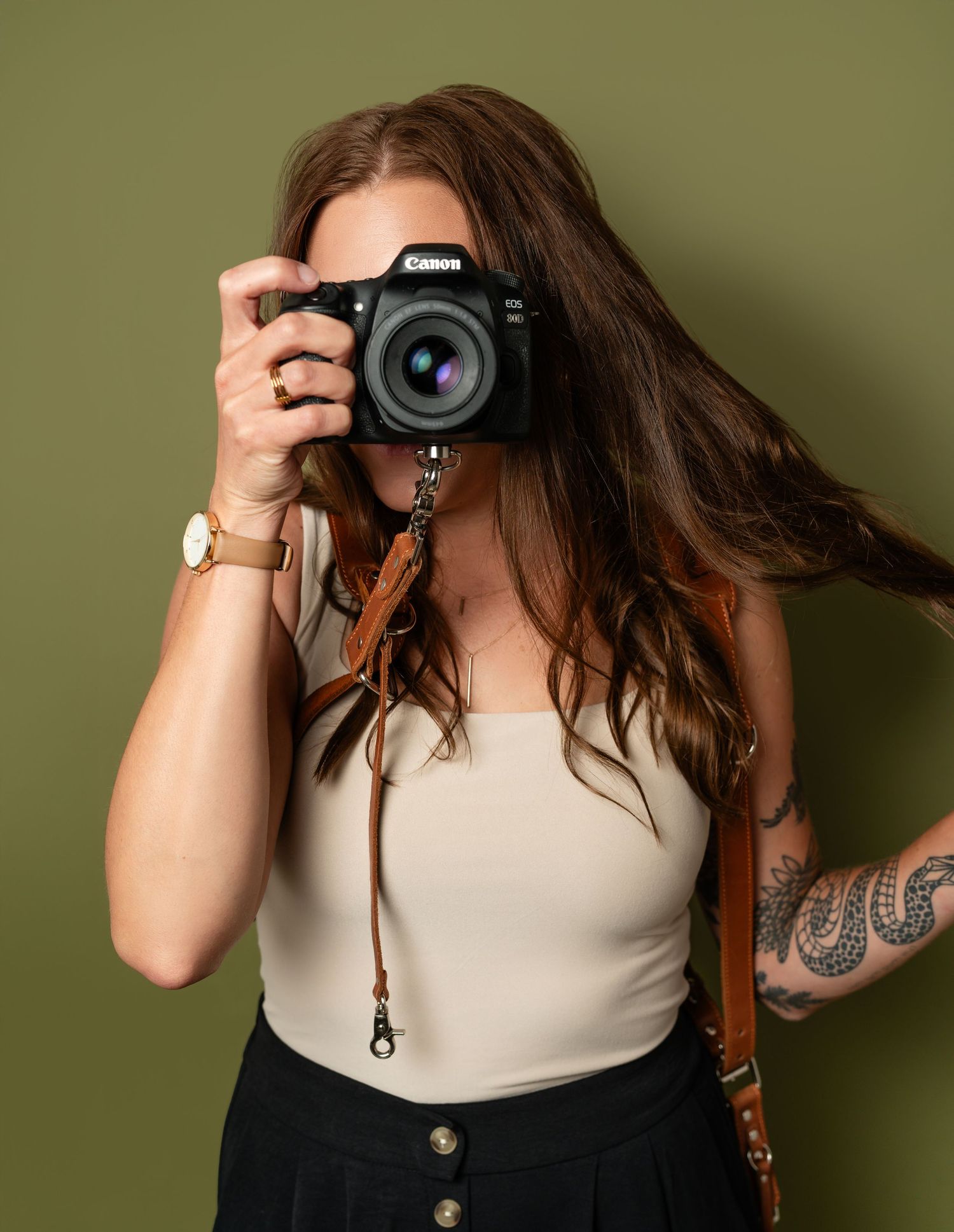 Professional photographer taking a photo with a Canon DSLR camera against a green background.