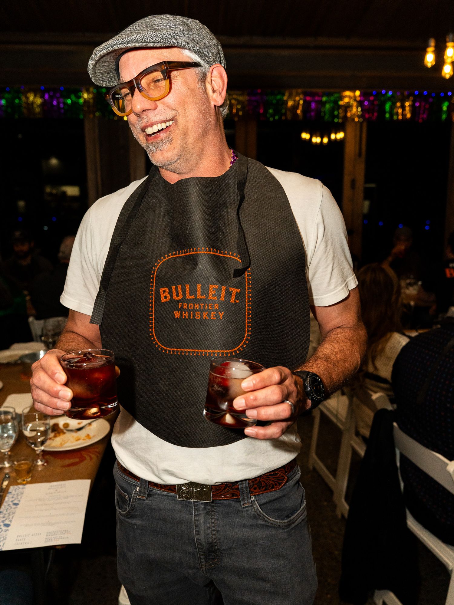 Restaurant worker in dark apron and cap serving food at a dimly lit venue.