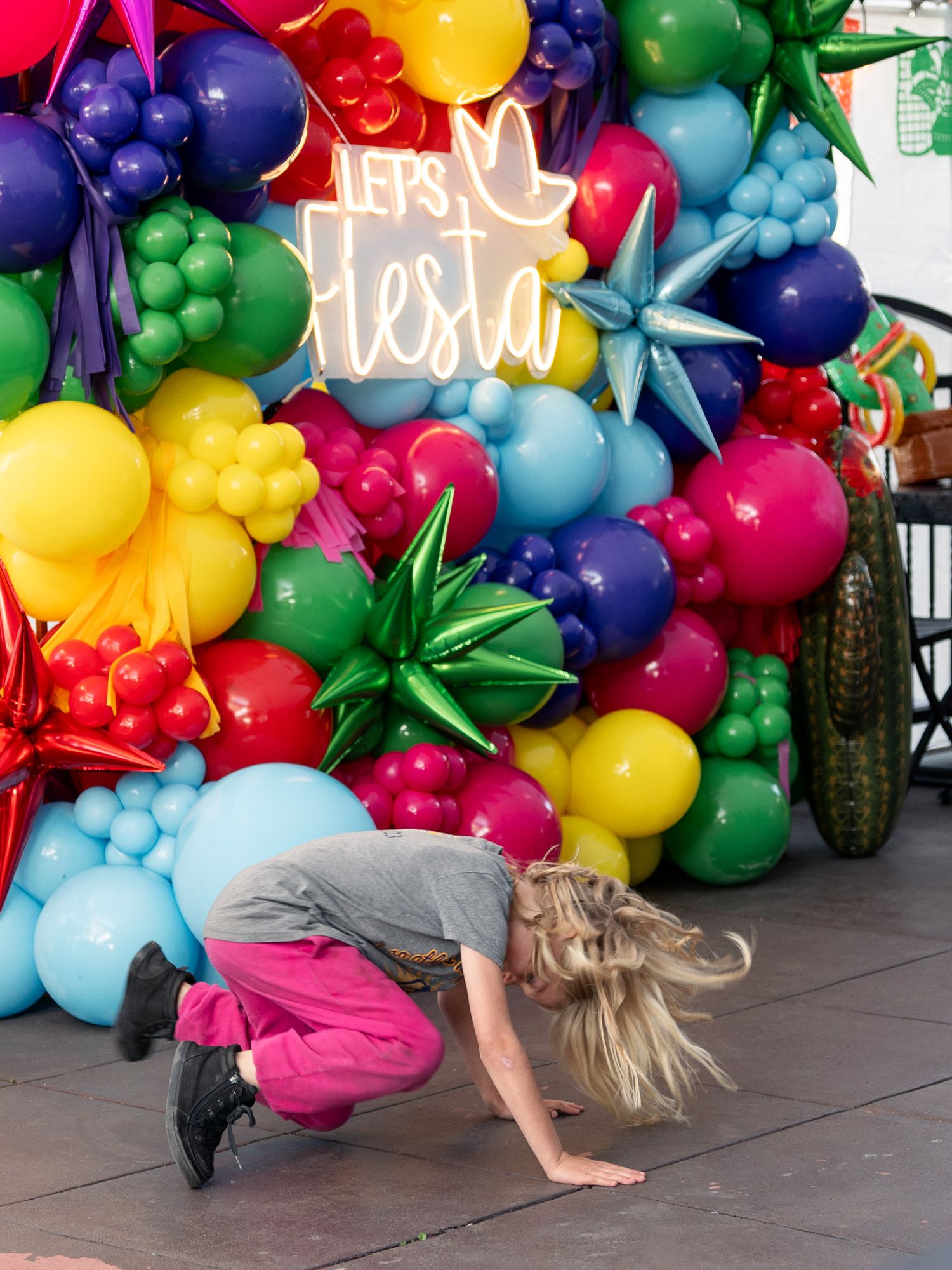 Dancer performing in front of colorful balloon display at fiesta celebration.