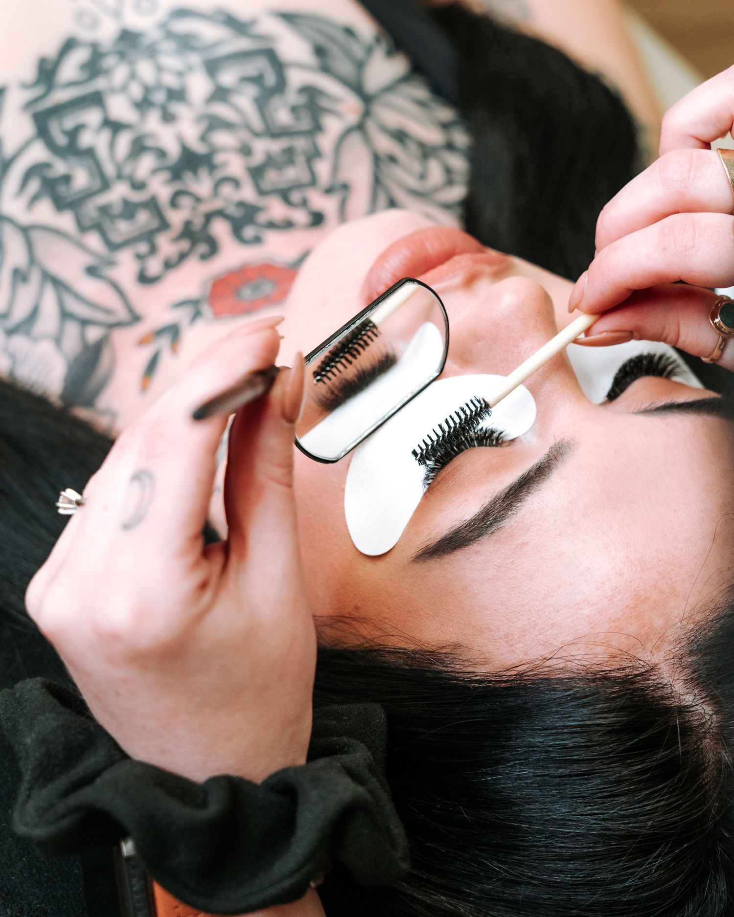 Eyelash extension application using professional tools and eye pads.