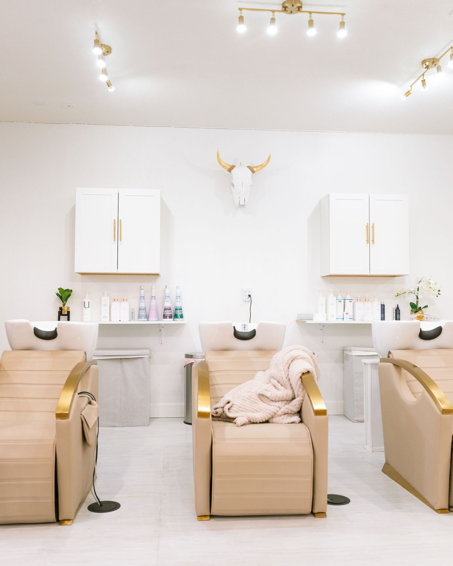 Spa treatment room with beige recliners and elegant white cabinets.